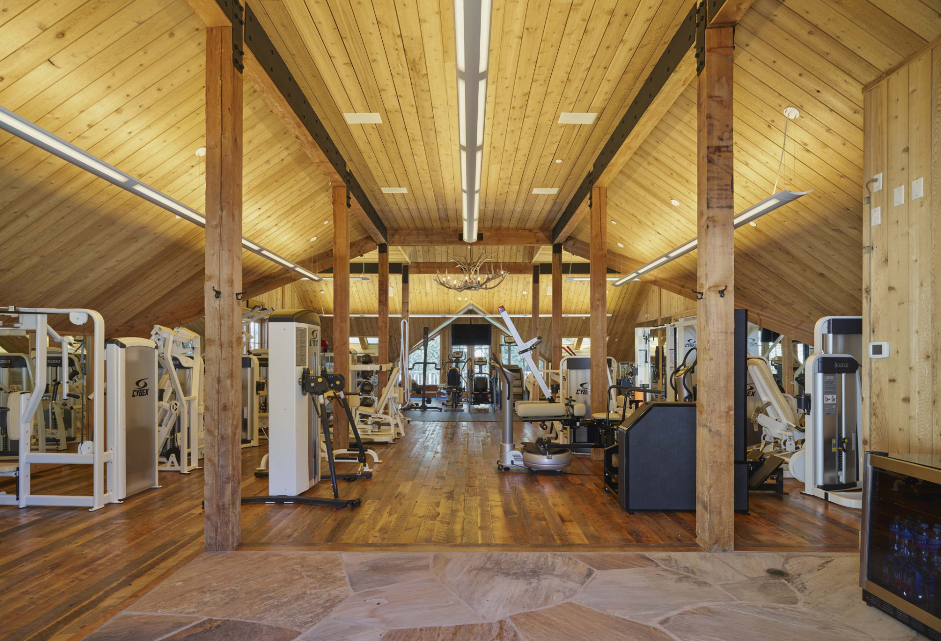A soaring vaulted ceiling houses an extensive collection of commercial-grade strength and cardio equipment, including weight machines, free weights, functional training stations, and exercise bikes. 