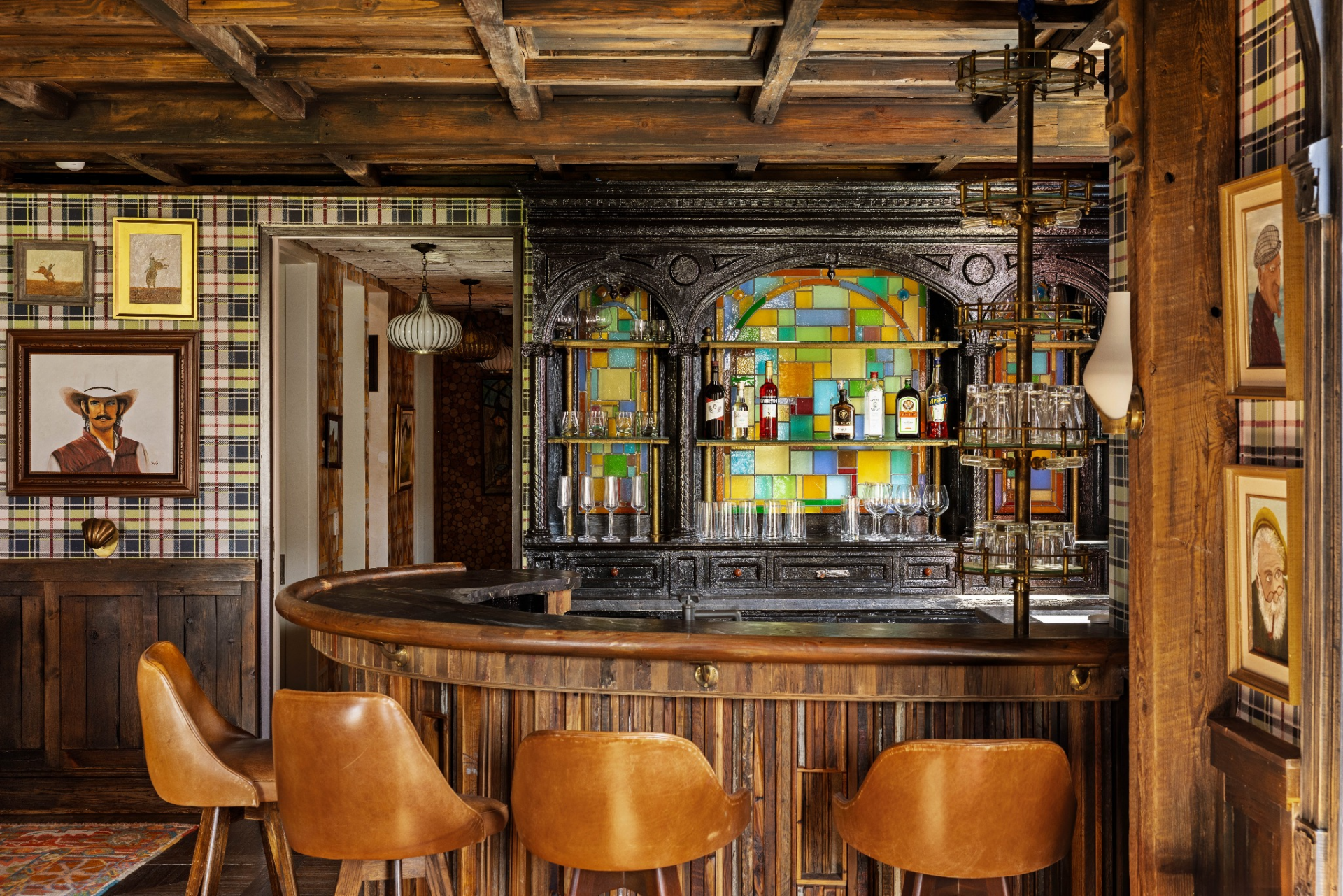 Leather bar stools, vintage-inspired shelving, and an integrated wet bar transform the area into the perfect place to entertain, separate from the home's more conventional living spaces.