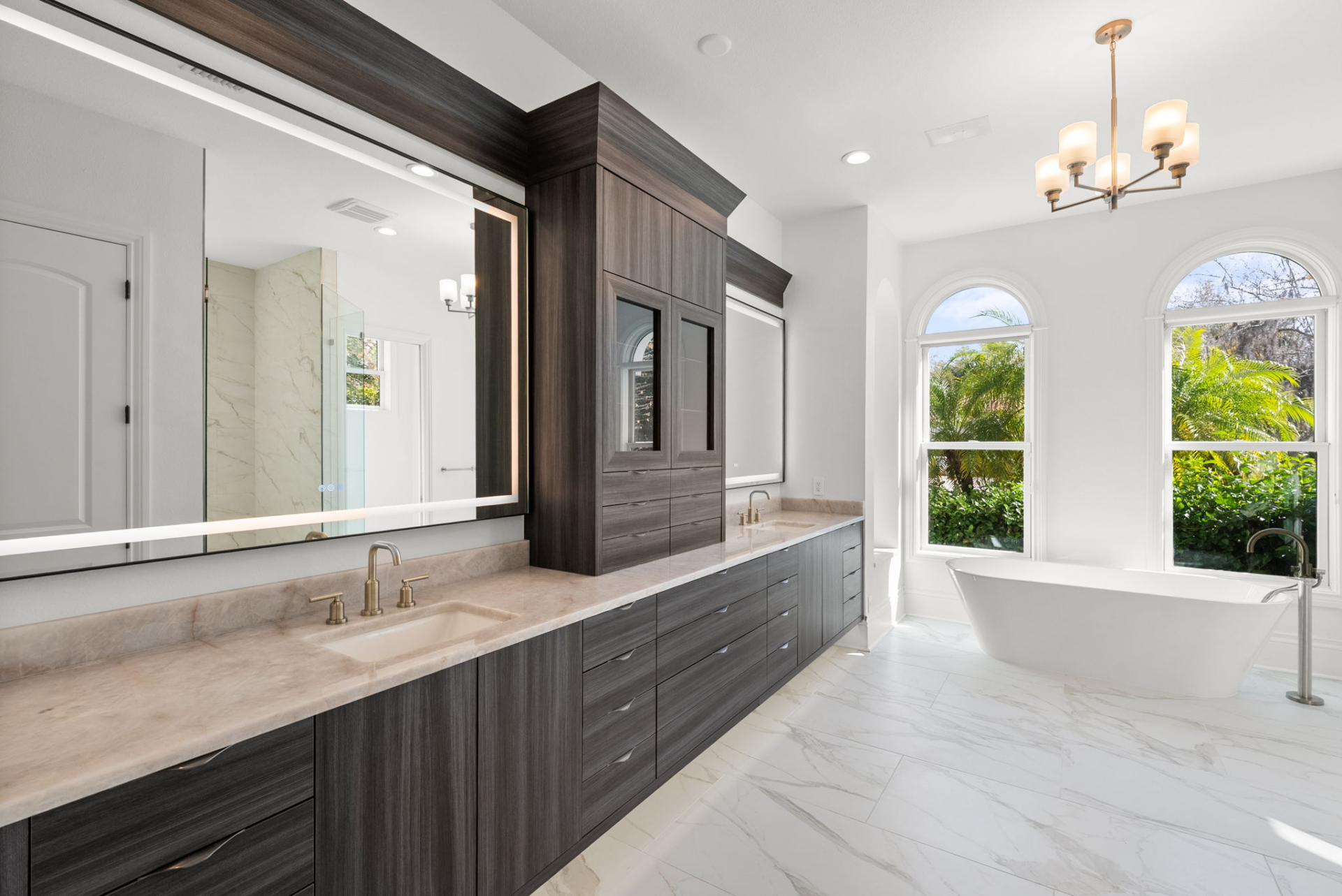 The en-suite bathroom features a long dual-sink vanity with extensive storage, complemented by custom cabinetry and illuminated mirrors.