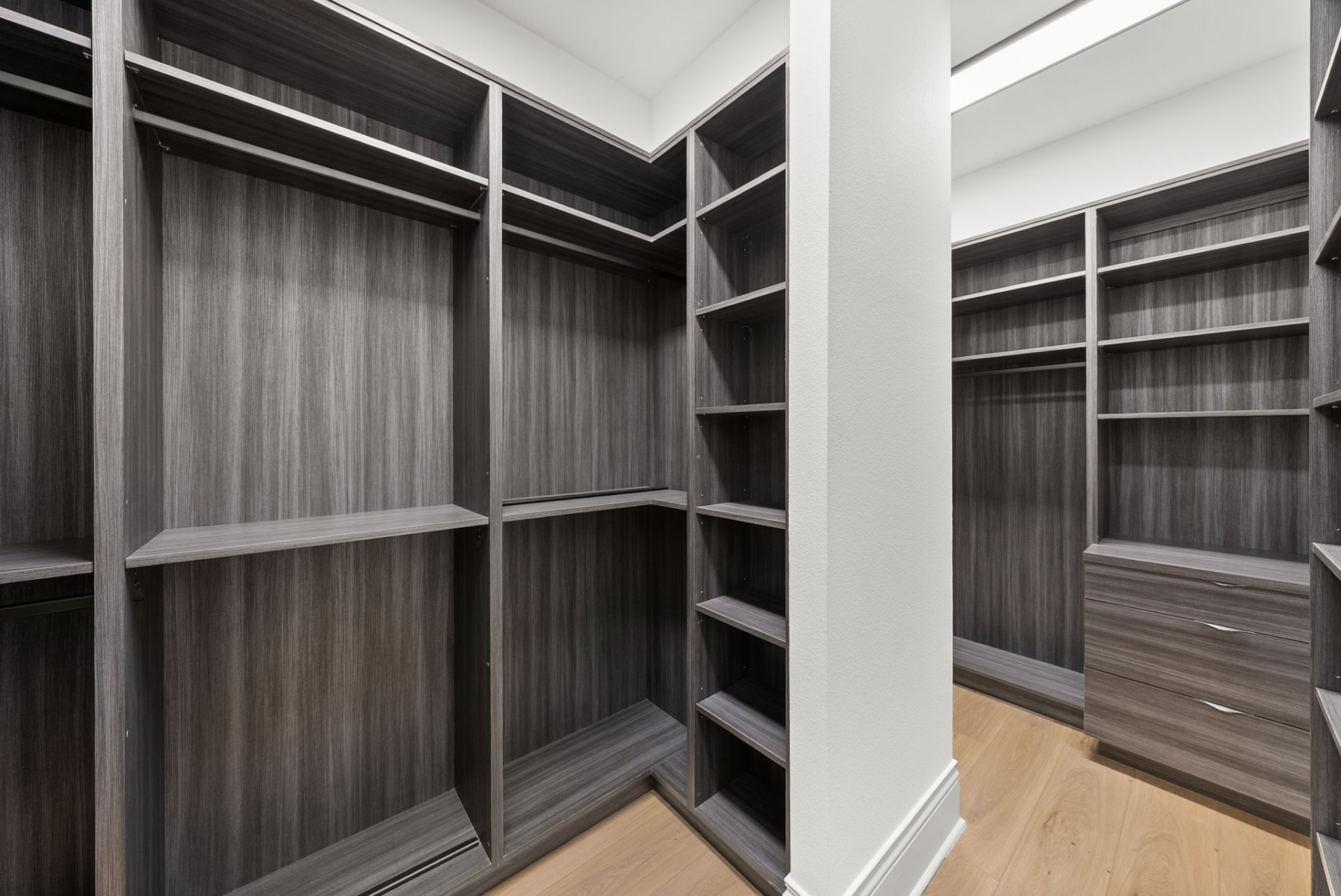 Completing the suite and connecting directly to the bathroom is a large walk-in closet fitted with custom built-ins, open shelving, hanging areas, and integrated drawers.
