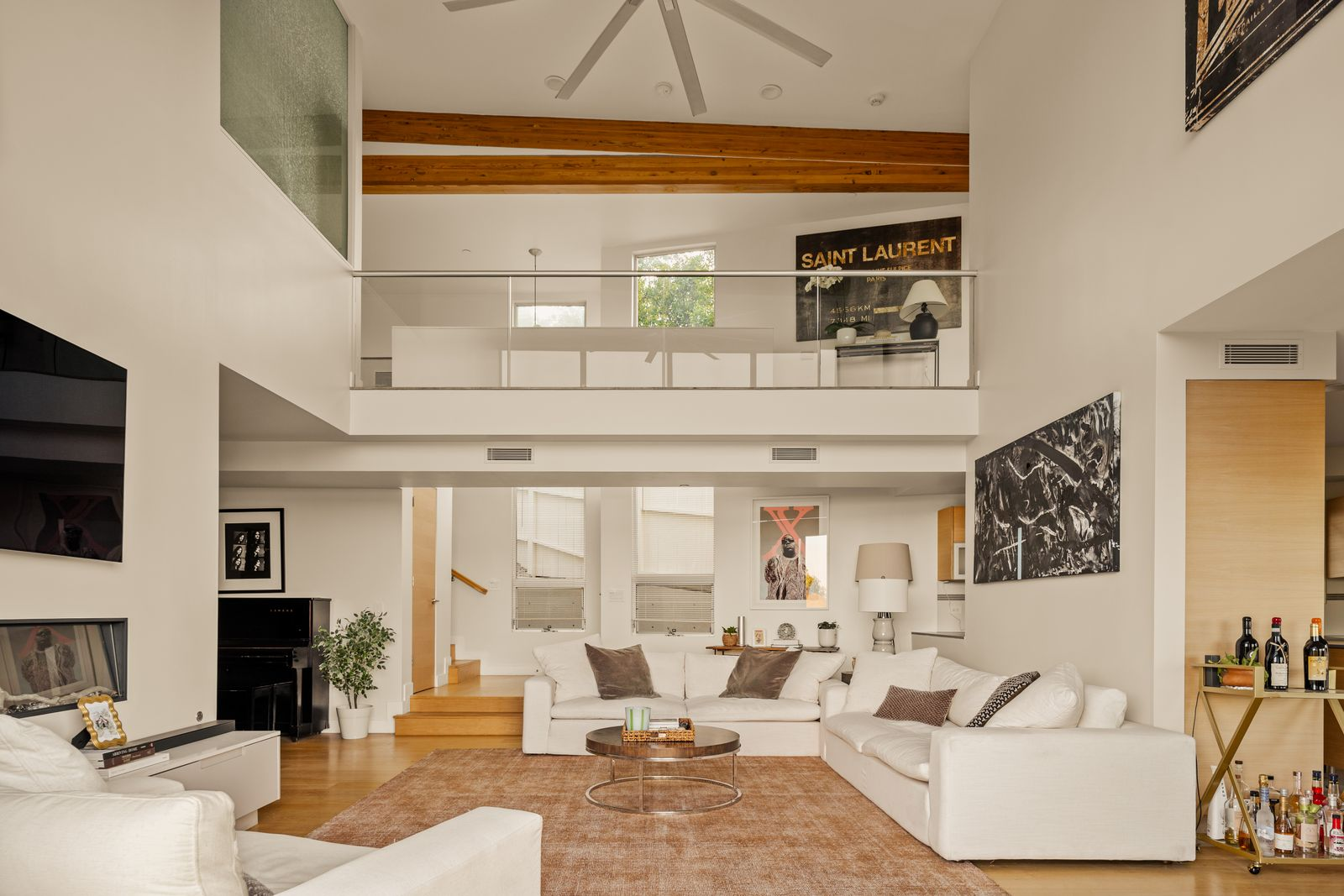 The two-story great room serves as the centerpiece of the home, with a linear fireplace, soaring 18-foot ceilings, and an open mezzanine that emphasizes the residence's dramatic sense of volume. 
