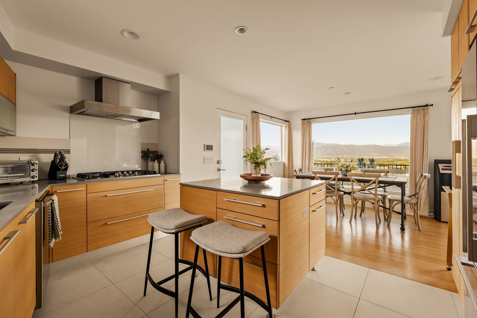 Quartz counters line the perimeter, while the kitchen's open connection to the dining area ensures the mountain and valley views remain visible throughout.