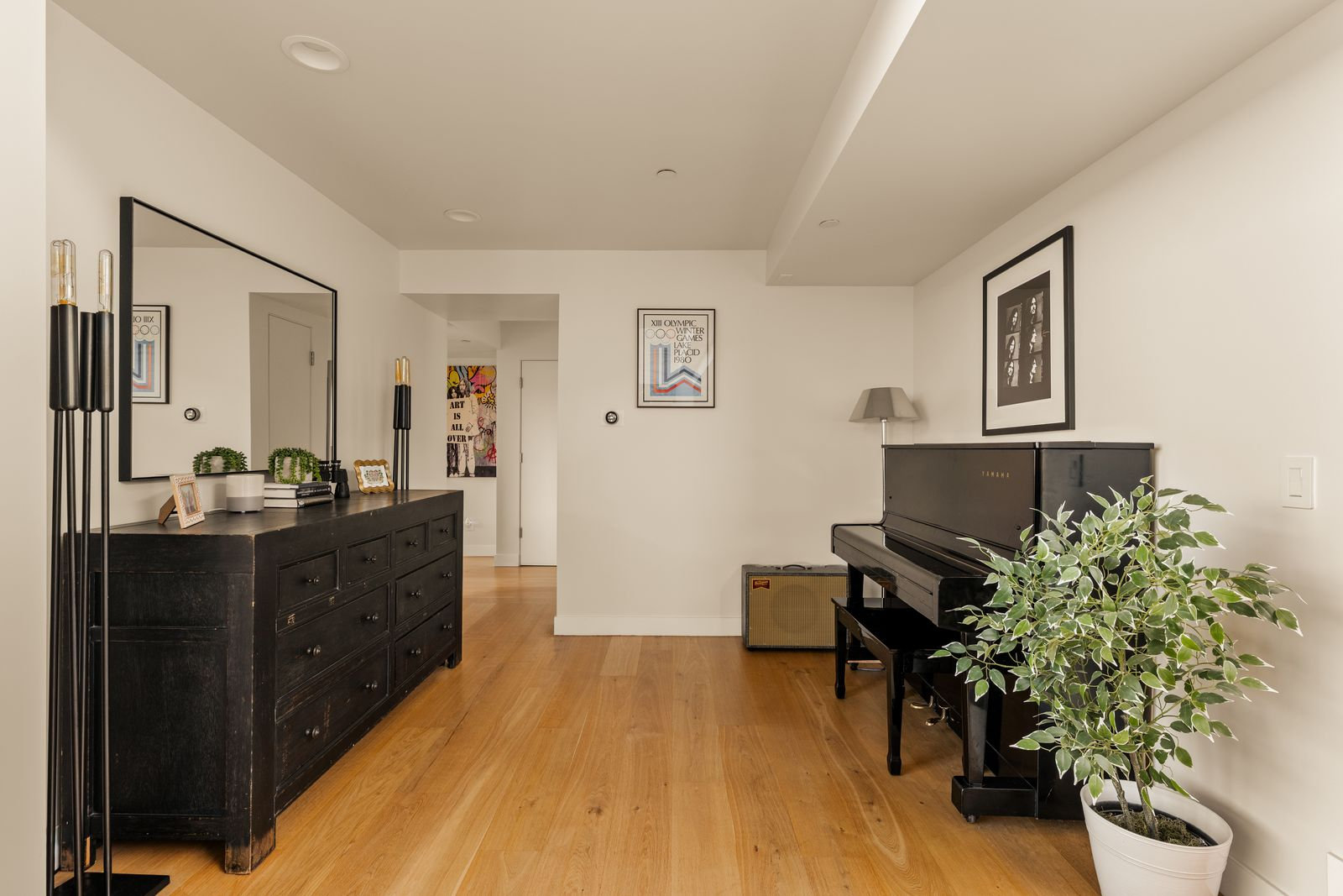 Warm hardwood floors continue into the space, where a black Yamaha upright piano serves as the focal point against a clean white wall.