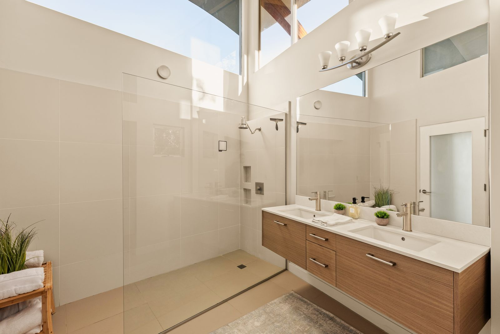 Just off the bedroom, the en-suite bathroom features double-height windows, highlighting the clean lines of the floating dual-sink vanity and oversized walk-in shower. 