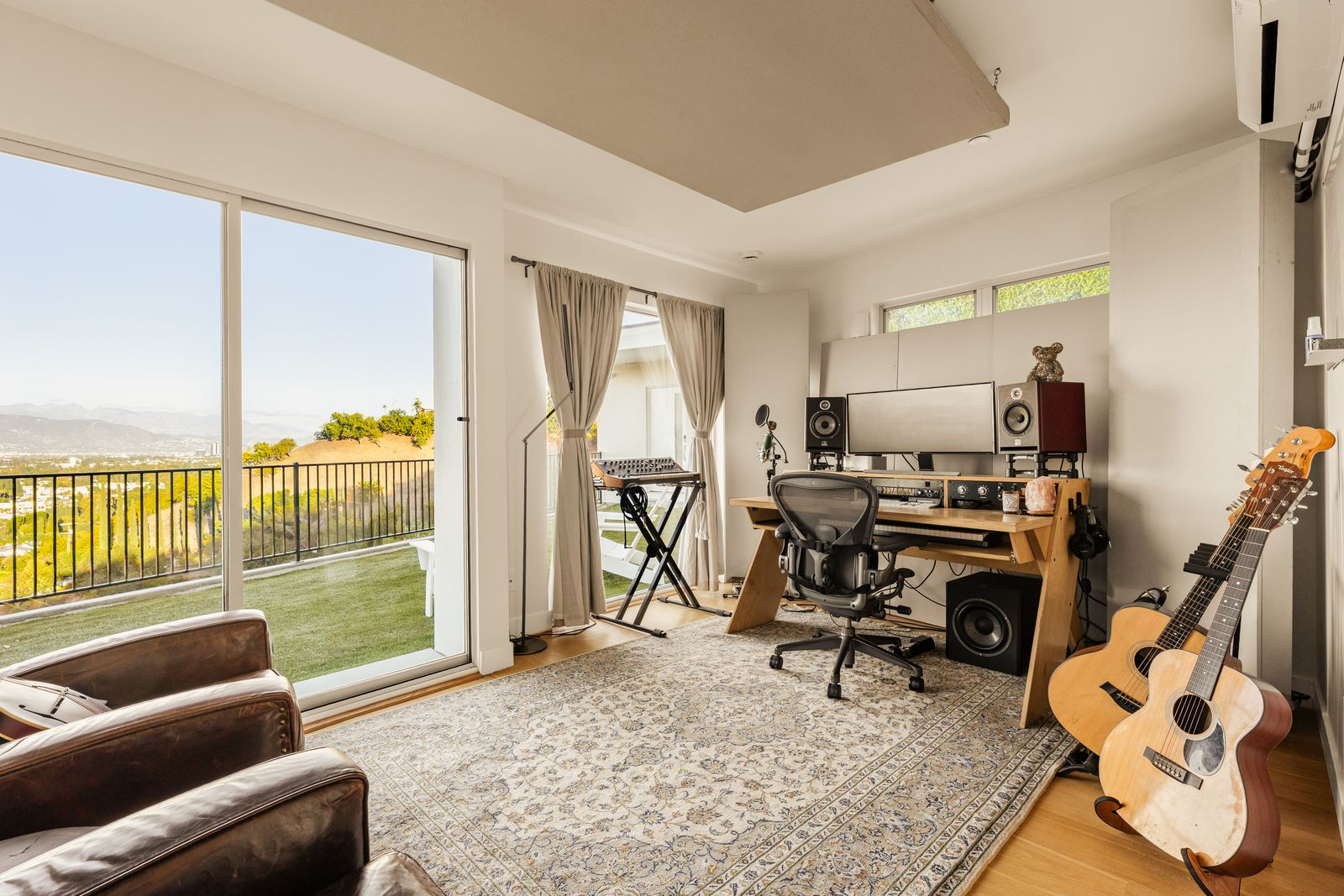 The space is configured around a professional recording setup, with studio monitors, production equipment, instruments, and a workstation.