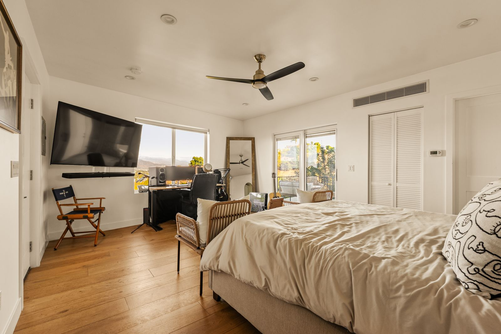 The main room is arranged as a flexible studio space, with enough room for a recording setup, seating area, and sleeping quarters with large windows framing hillside and valley views.