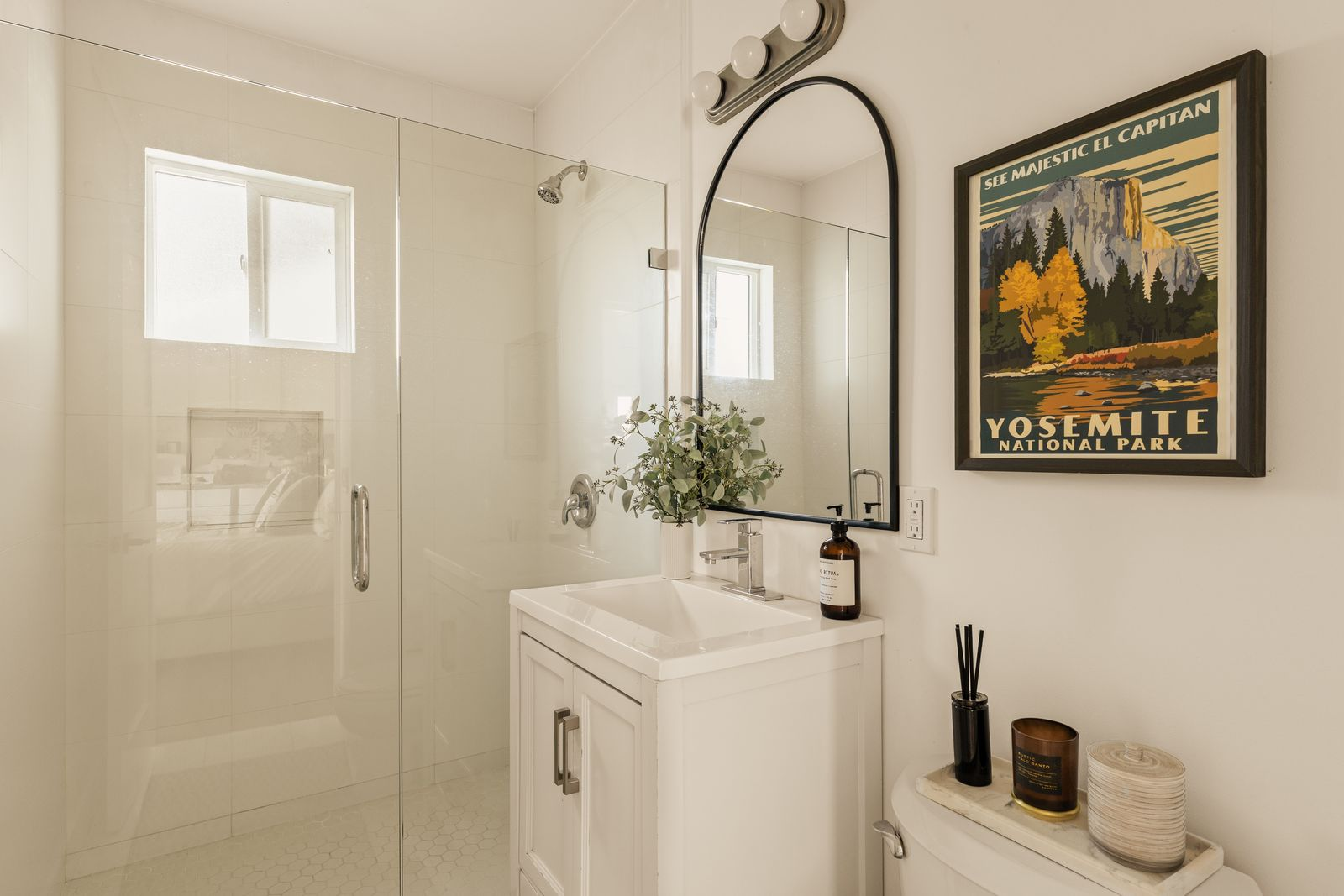 The connected bathroom continues the clean, modern design with a glass-enclosed shower, contemporary fixtures, and crisp white finishes. 