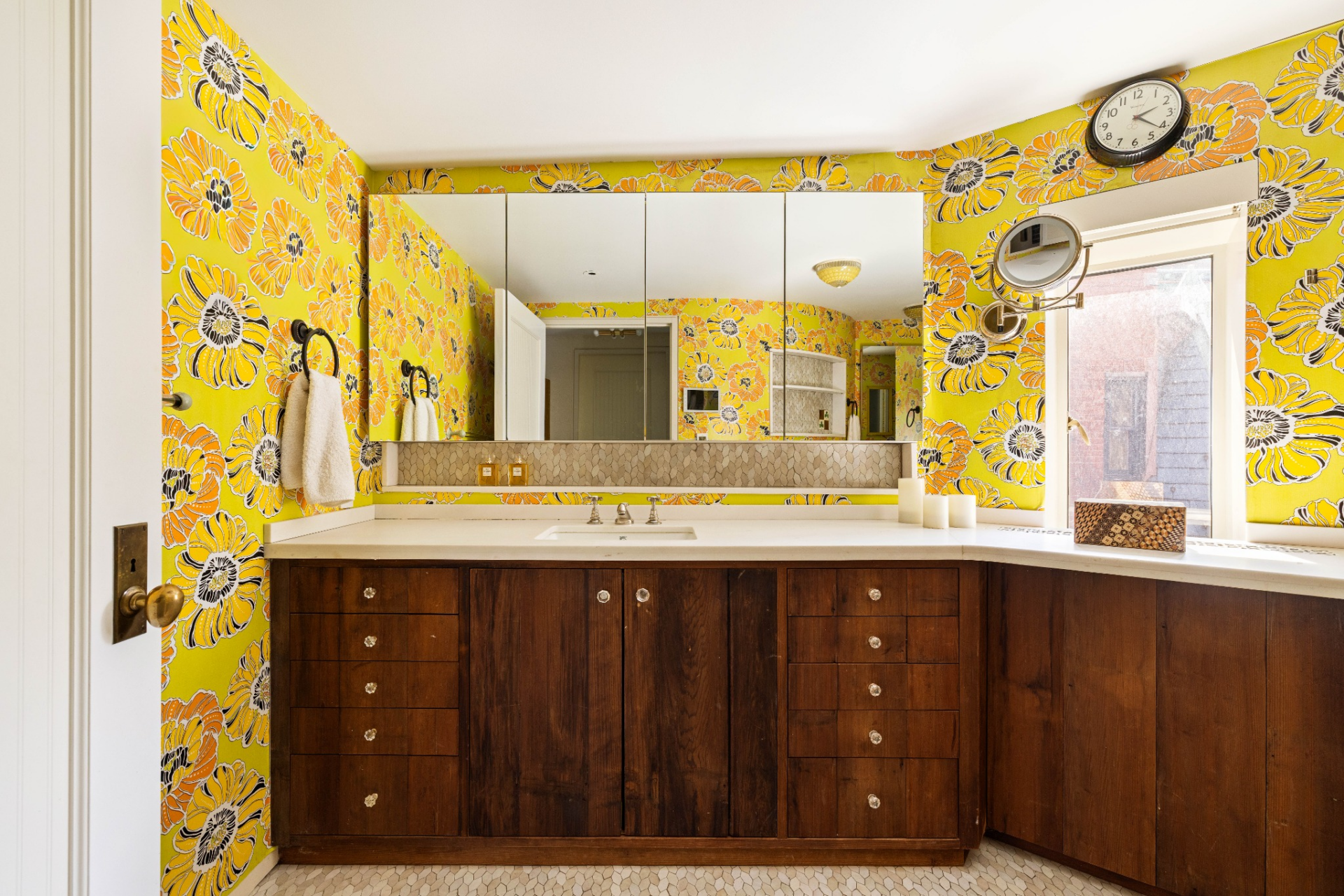 The vanity and steam shower room is covered in vibrant yellow floral wallpaper.