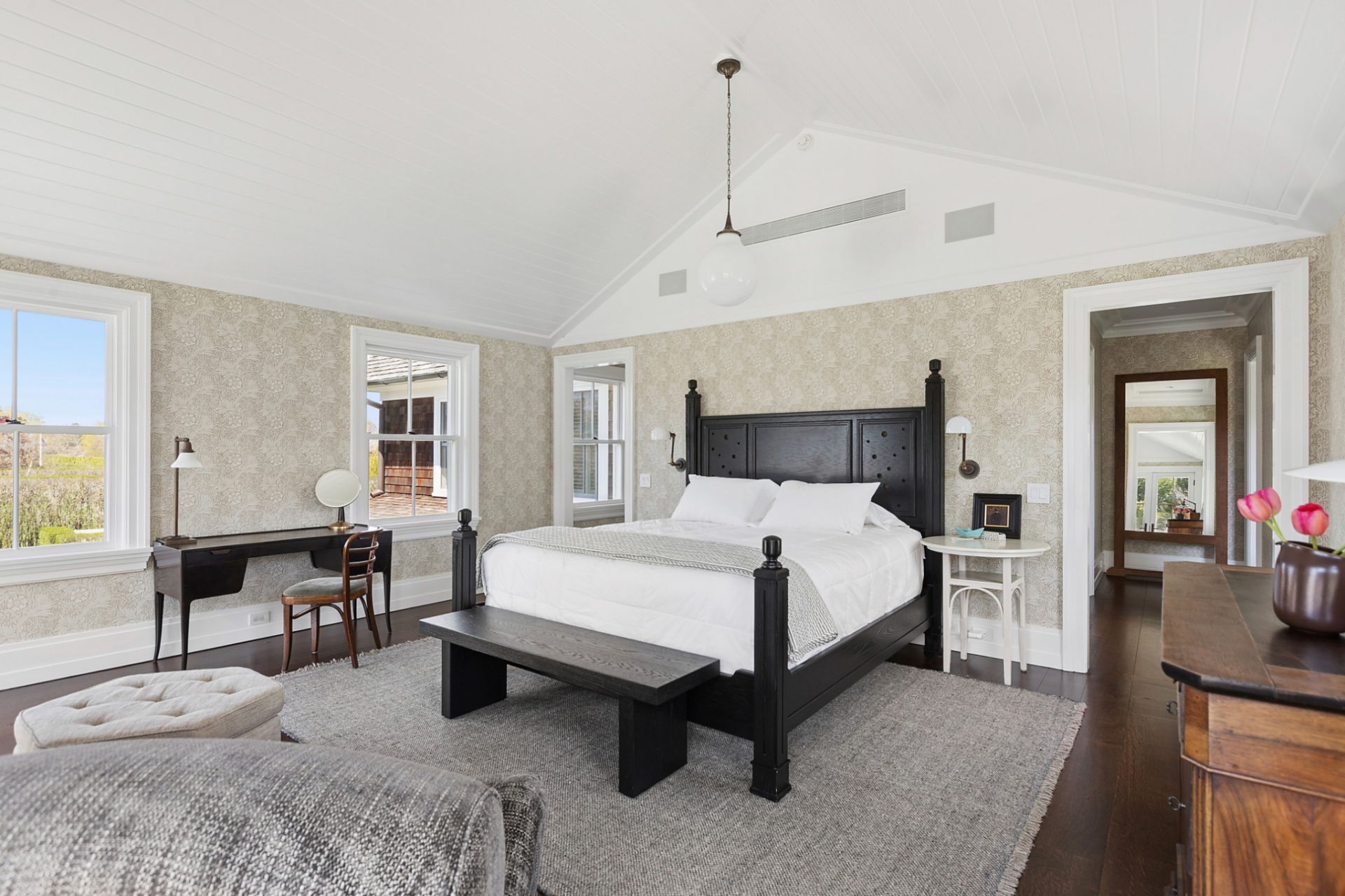 The sleeping area is centered around a four-poster bed, with a sitting area arranged near the fireplace for a quieter place to relax and a writing desk off to the side.