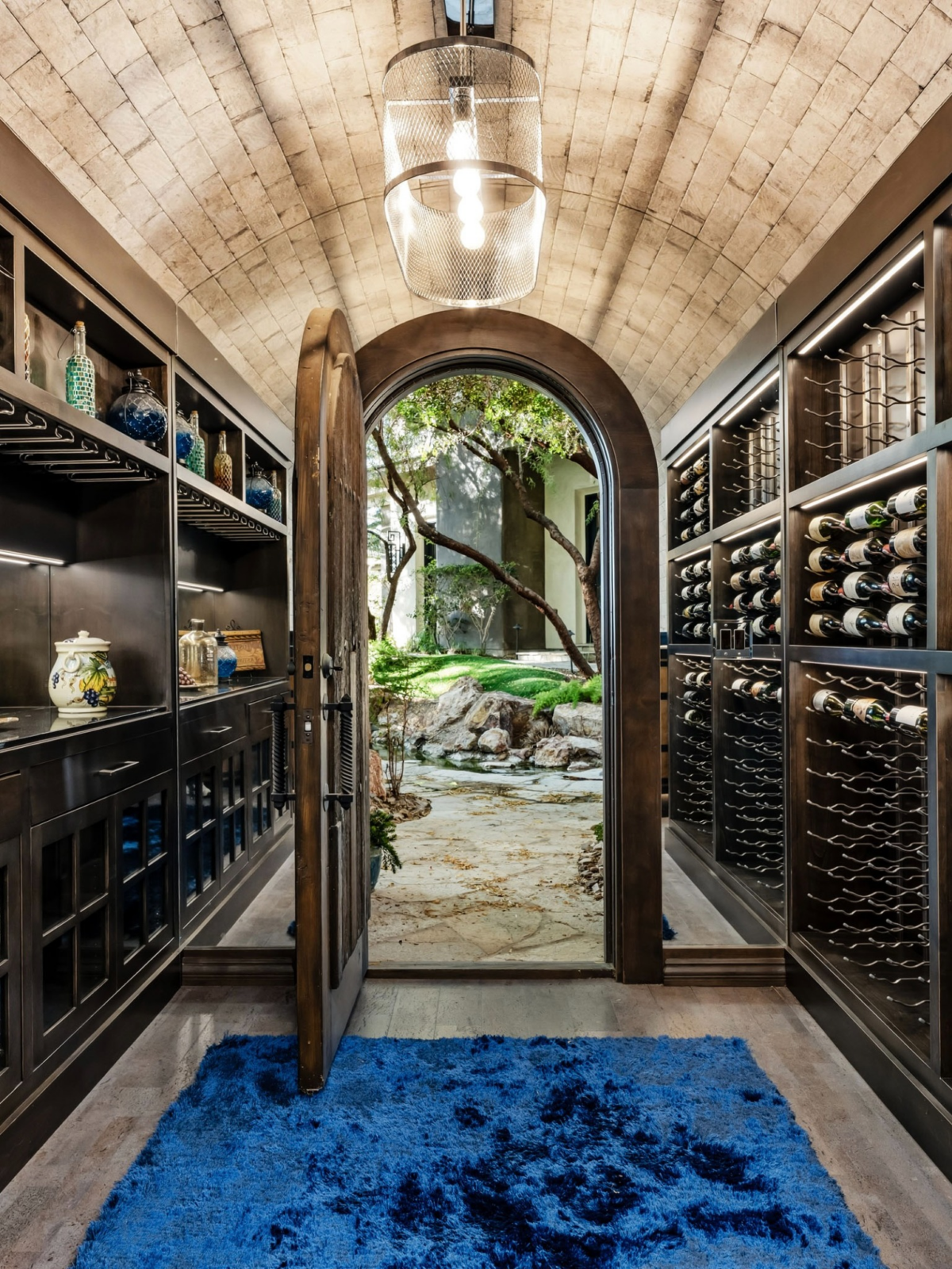 A temperature-controlled wine grotto, where dark wood cabinetry, custom bottle displays, and a vaulted ceiling create the atmosphere of a private tasting cellar.