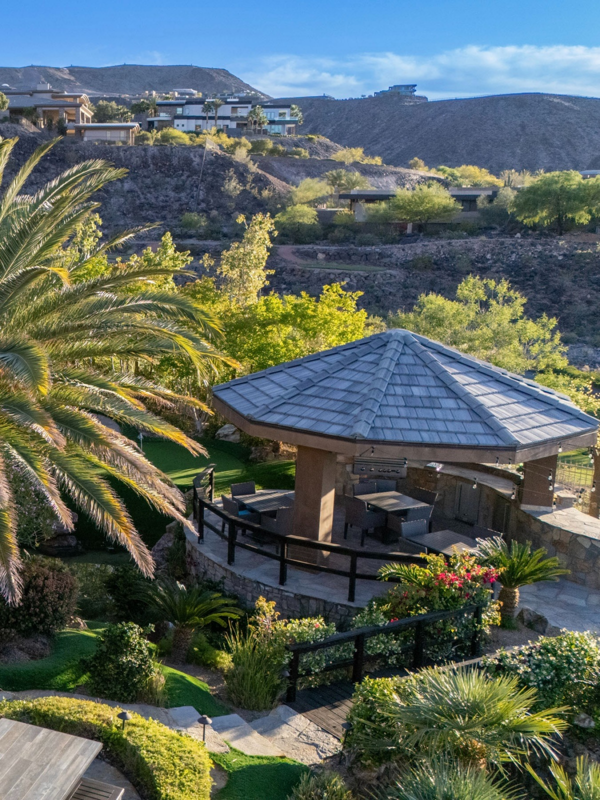 A fully equipped outdoor kitchen and pavilion create a dedicated space for entertaining, complete with bar seating and dining areas tucked among the landscaping.