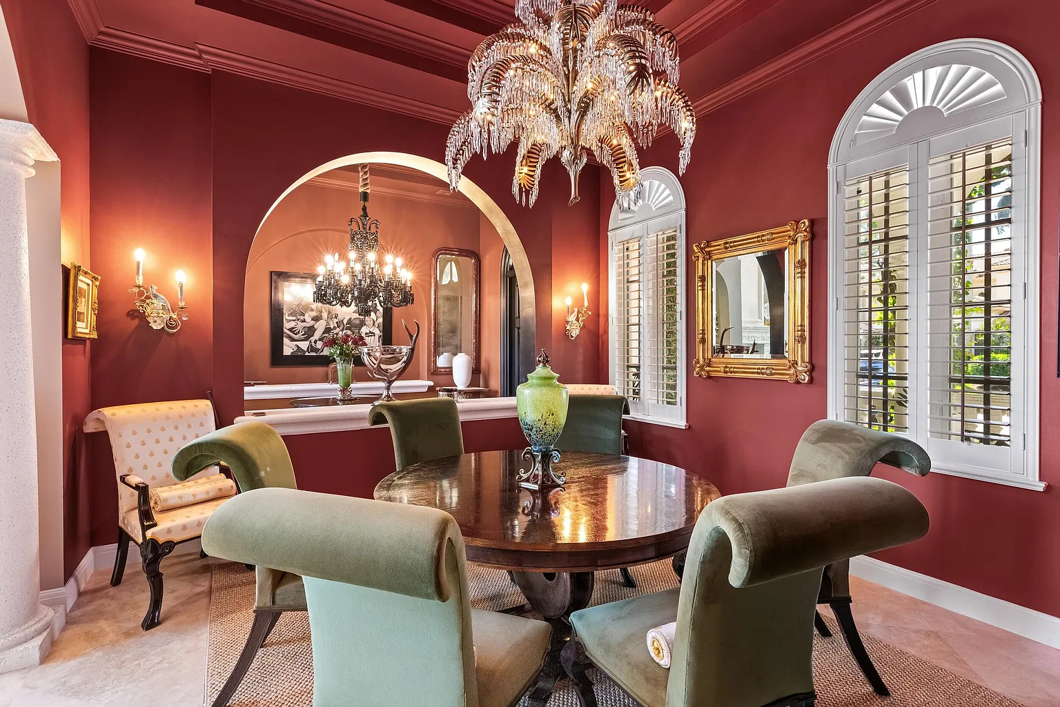 At its center sits a round wood dining table surrounded by green upholstered chairs, creating an intimate setting for dinners and smaller gatherings.