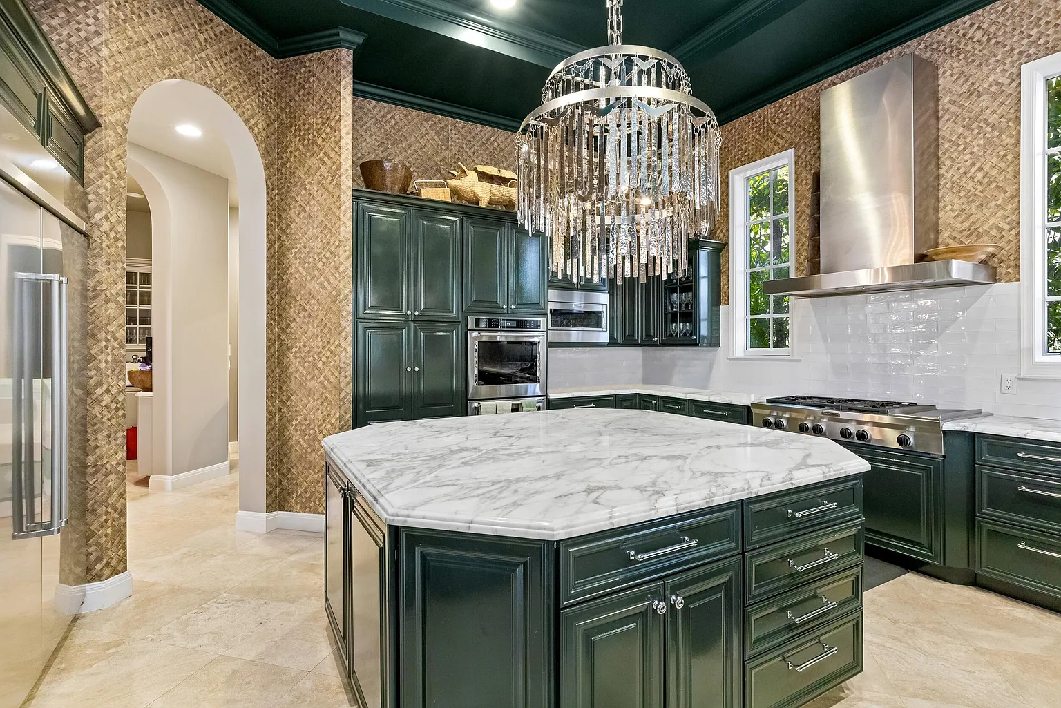 The chef’s kitchen combines dark green cabinetry with marble countertops and a white tile backsplash.