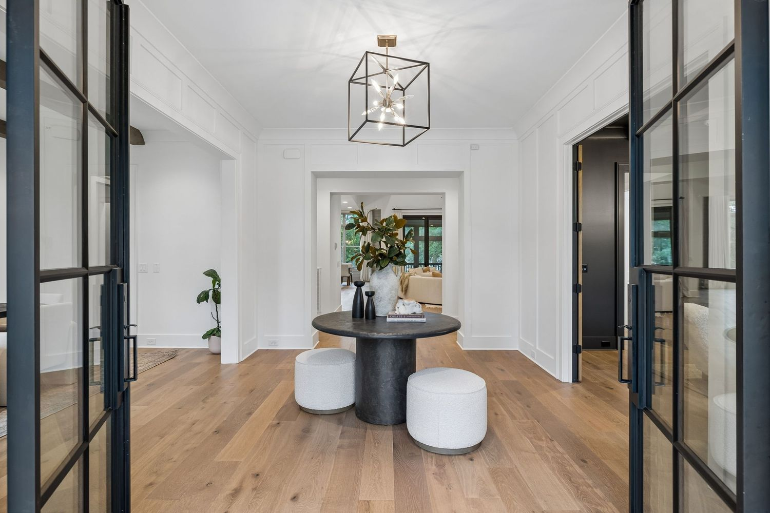 A round pedestal table positioned at the center serves as a simple focal point, while wide openings on either side provide access to additional rooms off the main hall.