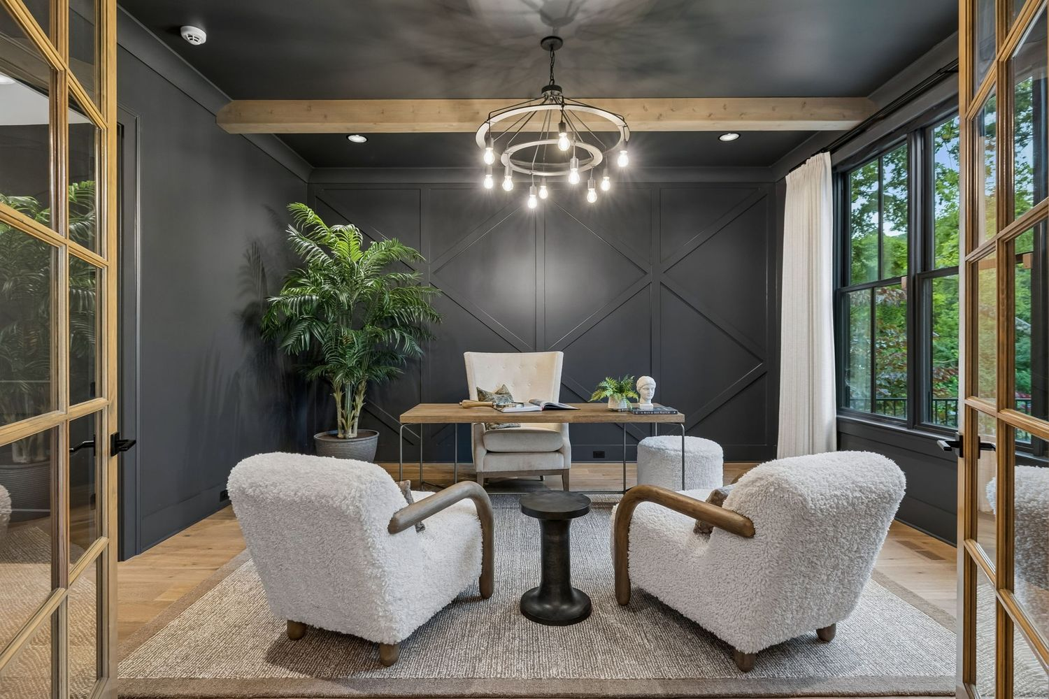 Across the foyer from the dining room, the front office is wrapped in deep charcoal walls with geometric panel detailing and a matching dark ceiling.