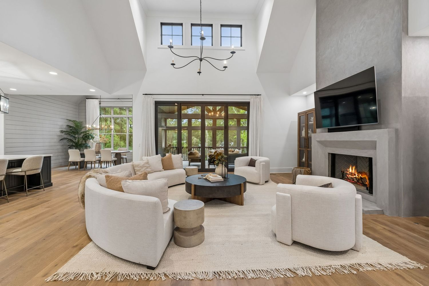 A dramatic great room with soaring ceilings that draw the eye upward to a series of clerestory windows and expansive glass doors that frame views of the backyard.