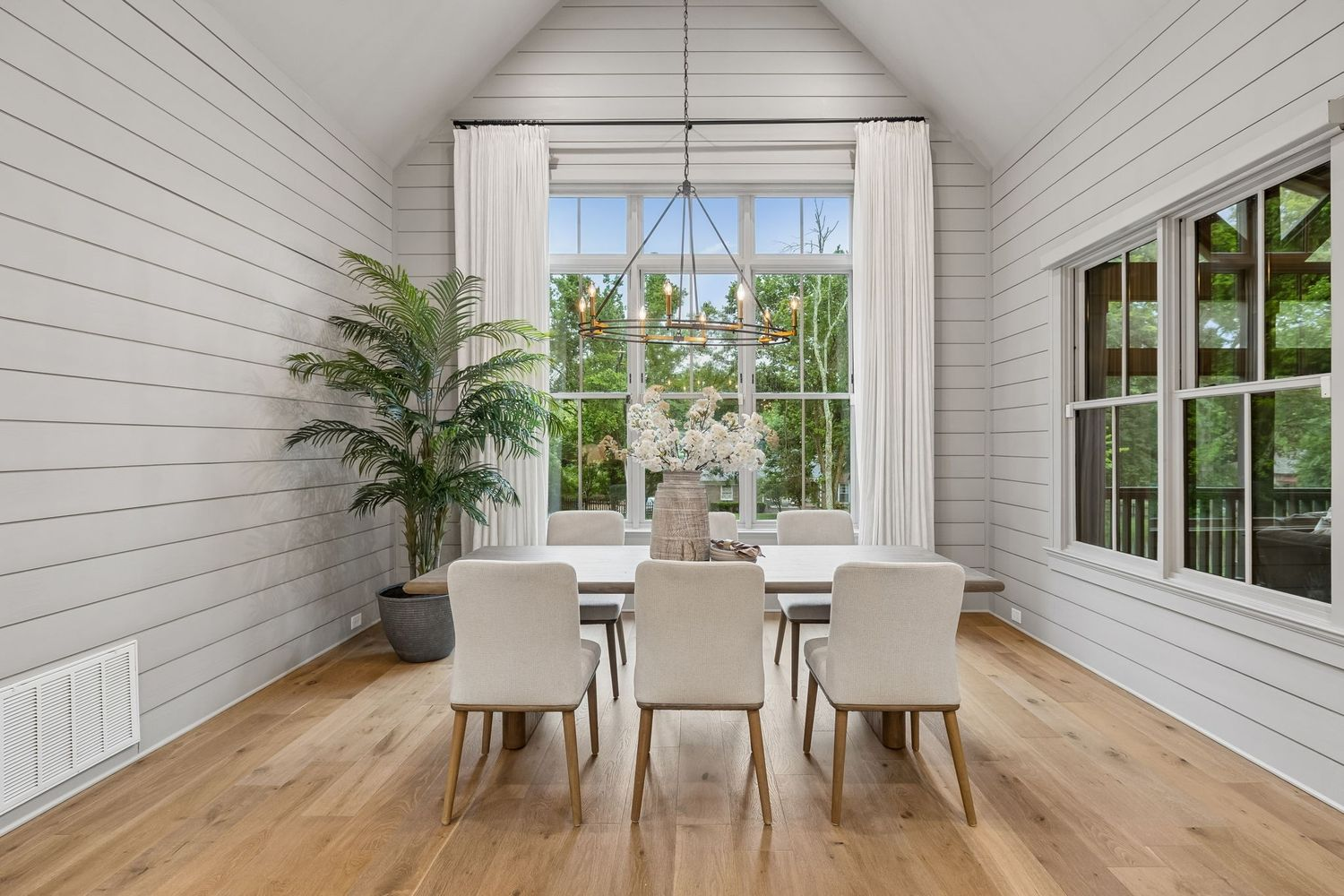 Just beyond the kitchen, a vaulted casual dining area is wrapped in shiplap walls and oversized windows that draw in natural light and views of the surrounding property.
