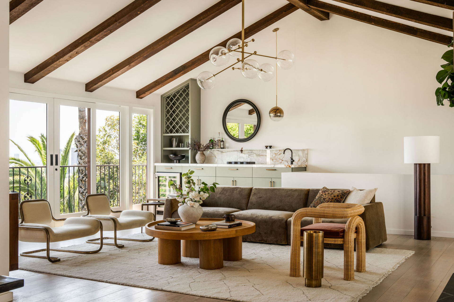 The main living room immediately establishes the home's hillside setting, with wall-to-wall windows and French doors.