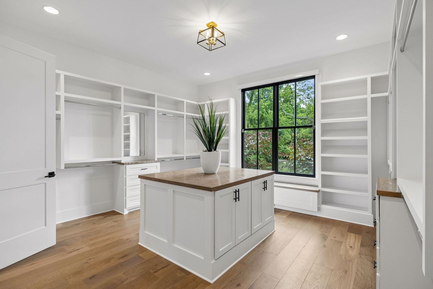 Open shelving, hanging sections, drawers, and display areas line the perimeter, while a large center island provides additional storage and folding space.
