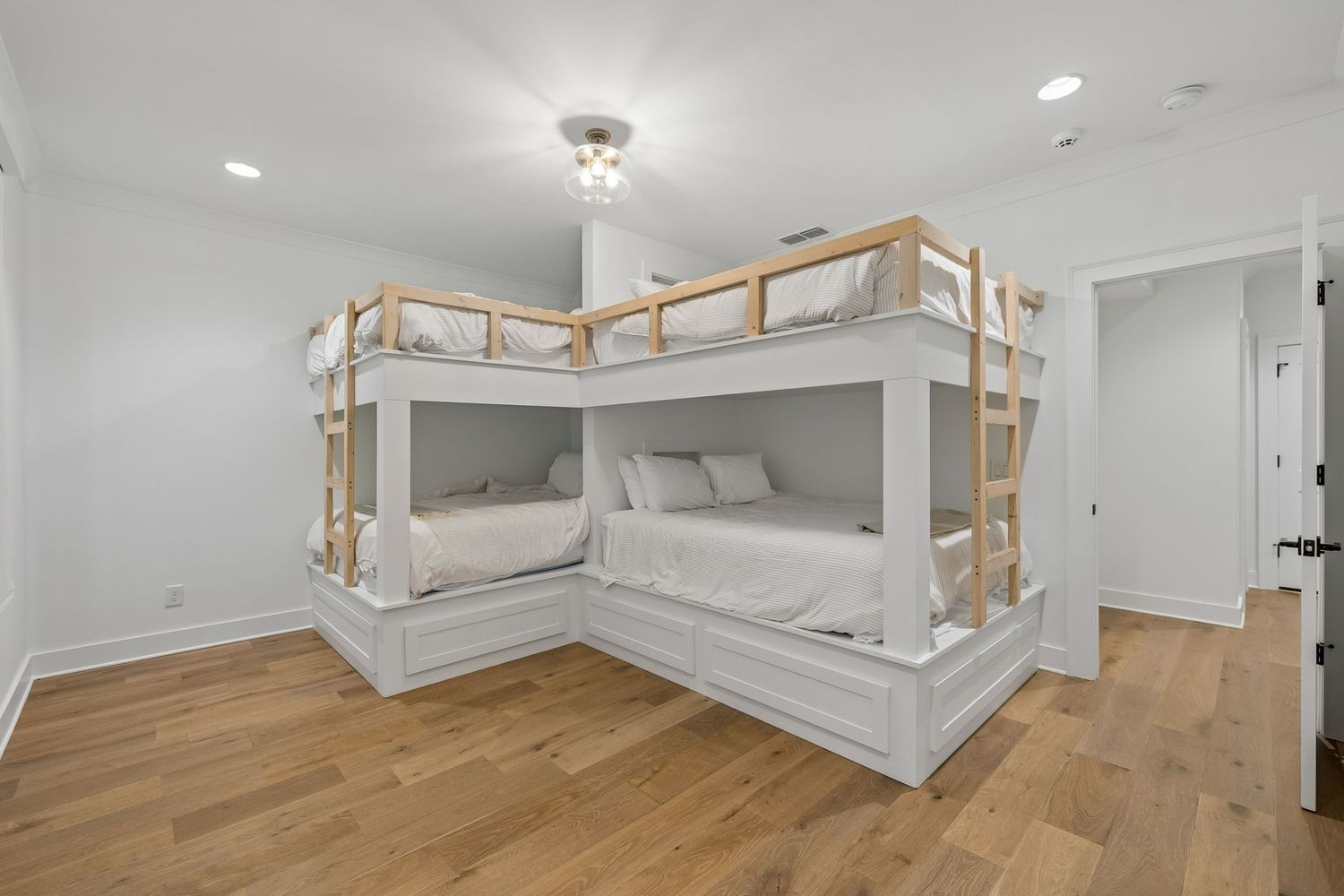 Built-in bunk beds are arranged in an L-shaped configuration, maximizing the room's space while creating multiple sleeping spaces within a single room.
