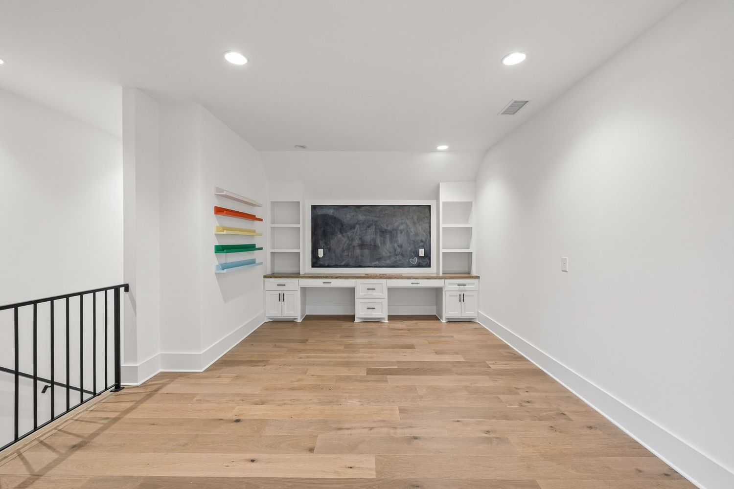 Built-in desks provide room for multiple students to work side by side, while open shelving and cabinetry offer storage for books and supplies around a large chalkboard.