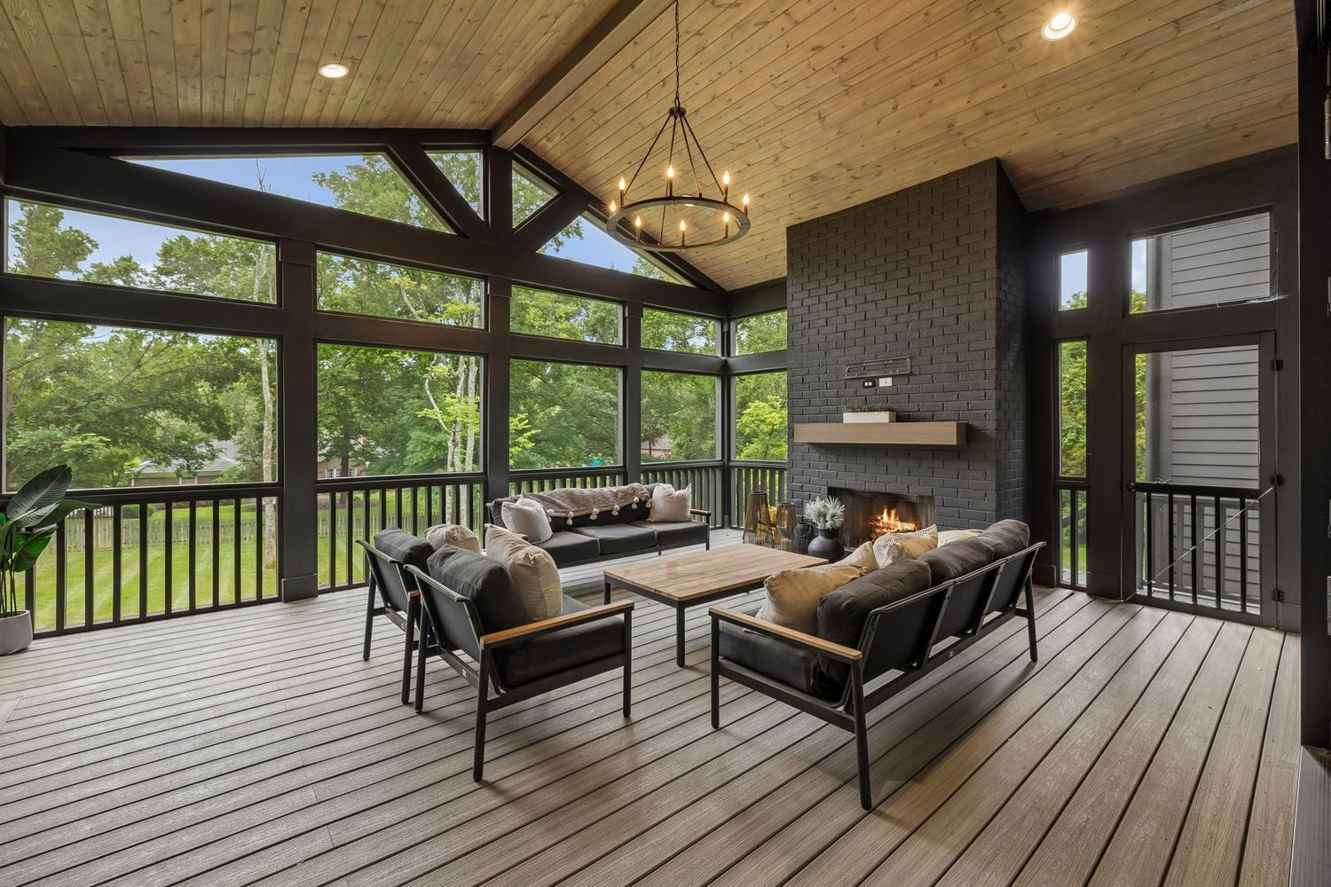 Just outside the main living areas is a spacious screened porch with a black brick fireplace, creating a center gathering spot amongst the outdoor lounge.