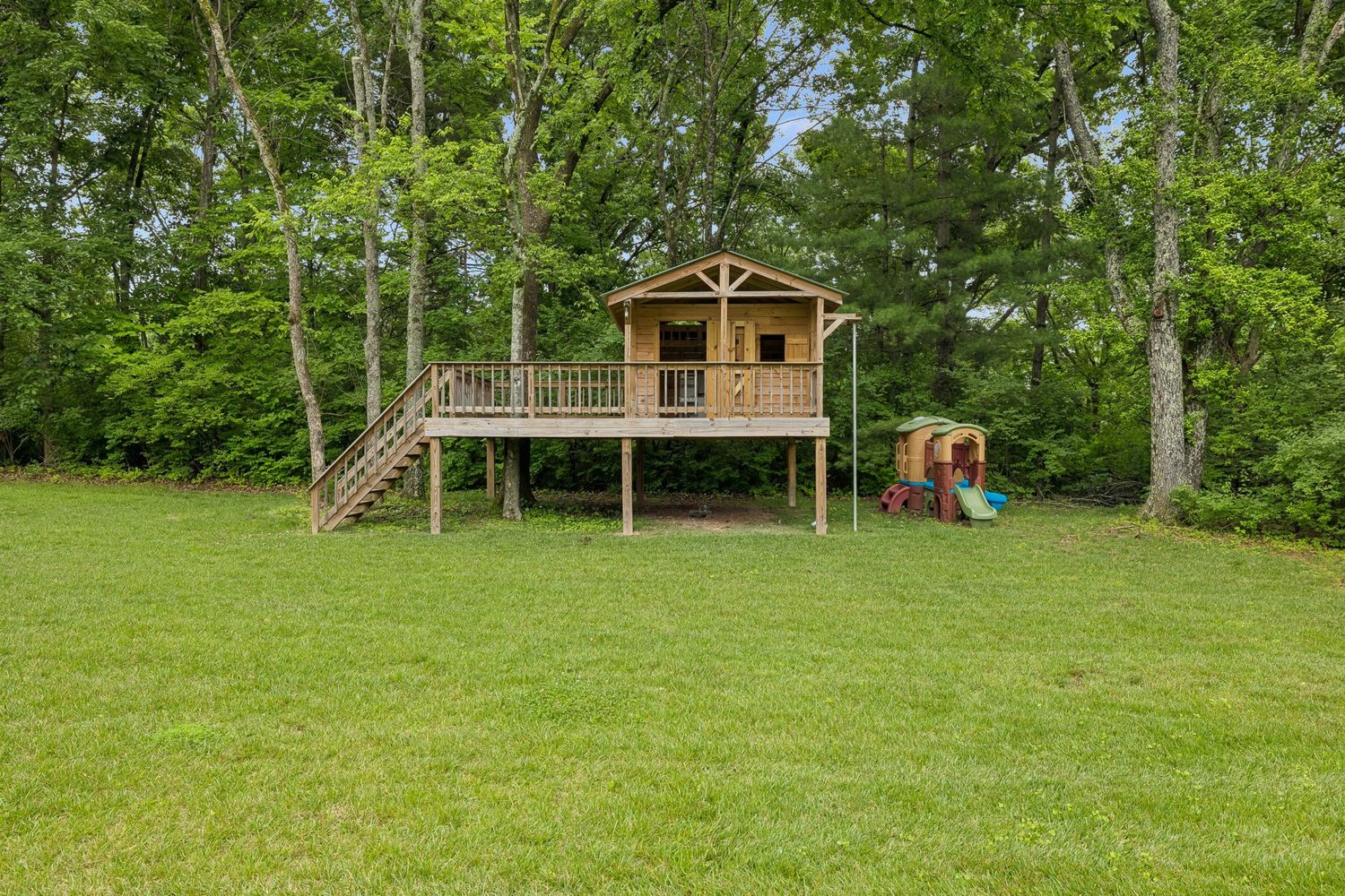 Tucked farther back along the tree line is a second play space centered around an elevated wooden playhouse with its own deck and lookout point.