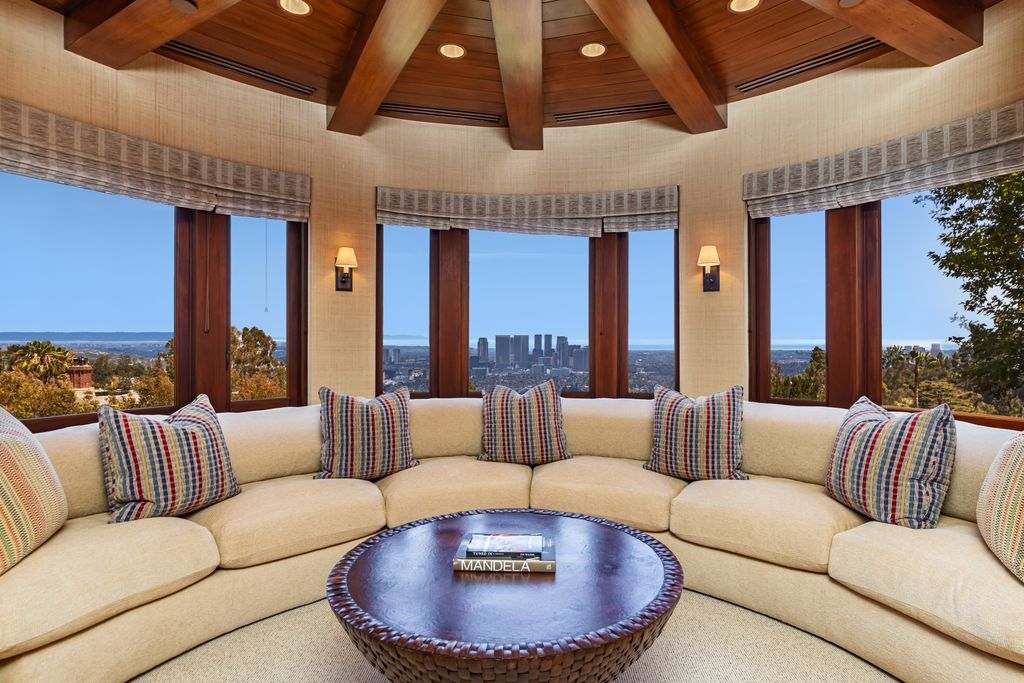 At the far end of the office, a raised sitting area curves around a wall of windows that frame views of the city.
