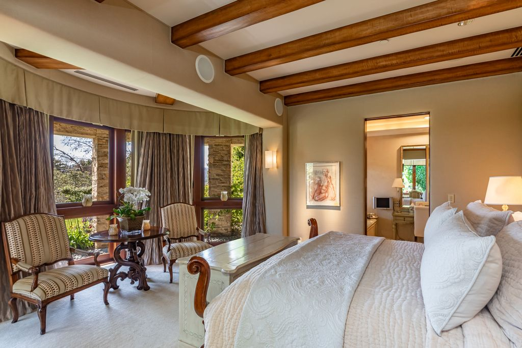 A sitting area tucked beside the windows creates a quiet place to relax across from the bed.