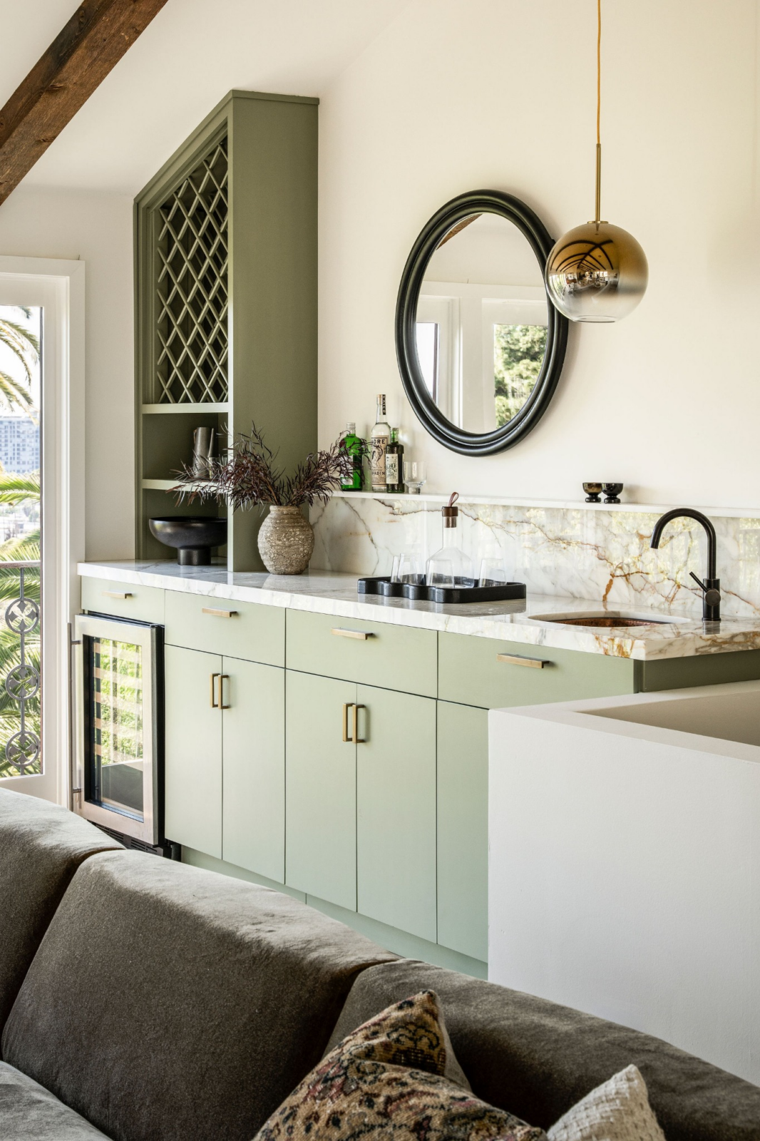 The bar is finished with sage-green cabinetry, a marble countertop, integrated wine storage, and a beverage refrigerator.