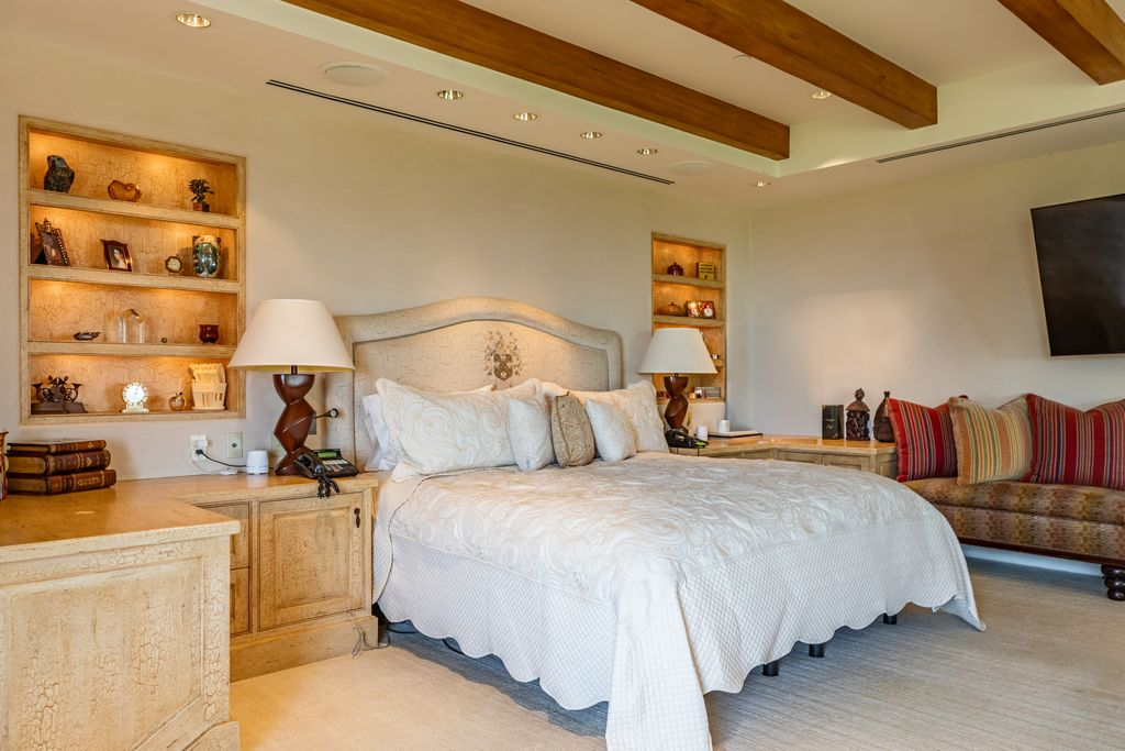 Heading into the private spaces, the primary suite occupies its own wing of the home beneath exposed wood beams.