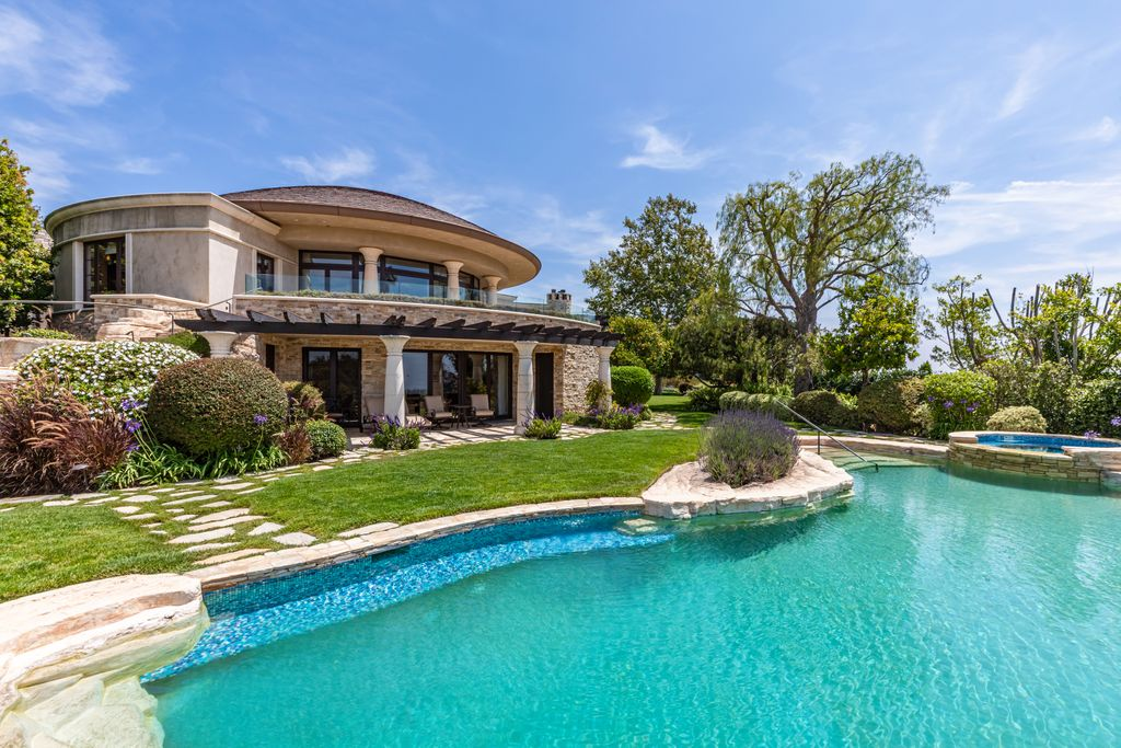 At the center of the backyard is a resort-style infinity-edge pool that curves through the landscape with natural stone detailing and an elevated spa.