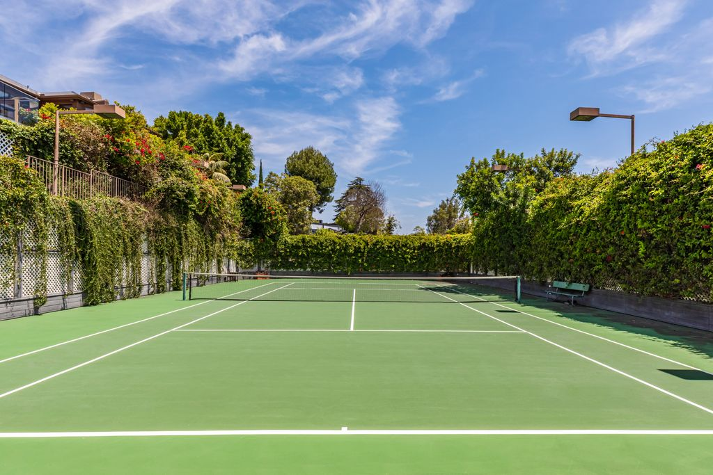 Tucked into a separate section of the grounds is a full-size lighted tennis court surrounded by tall hedges and mature greenery.