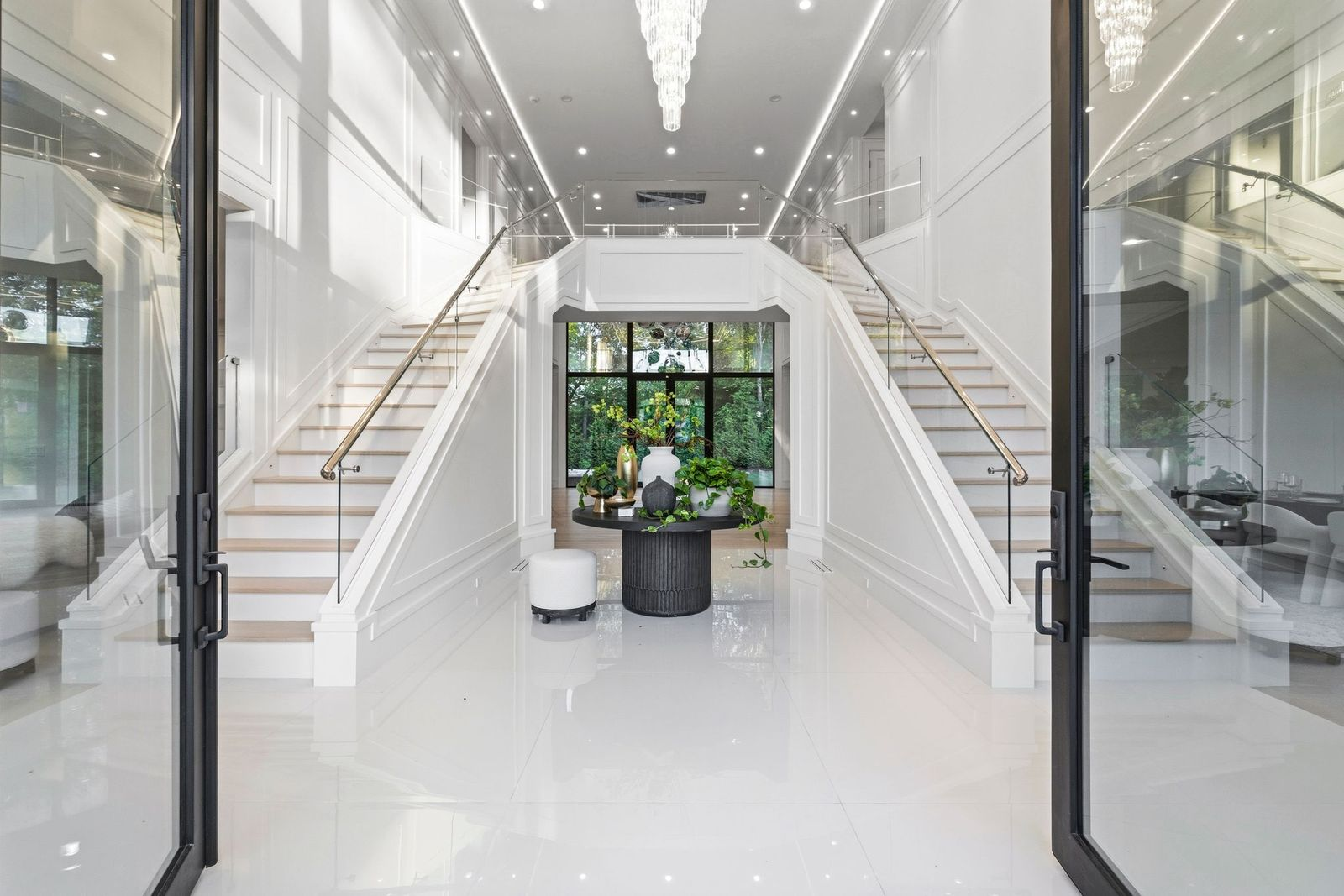 A dramatic two-story foyer centered around a pair of glass-lined staircases that rise around a central display table.