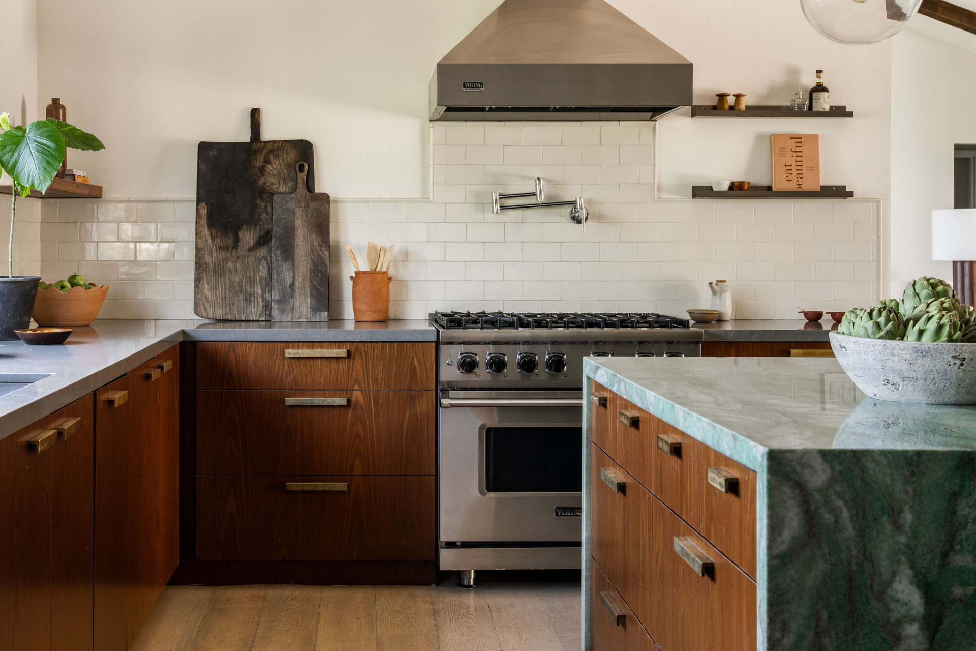 Professional-grade appliances are integrated throughout, including a Viking range beneath a stainless steel hood, while open shelving and a clean subway tile backsplash keep the walls feeling uncluttered.