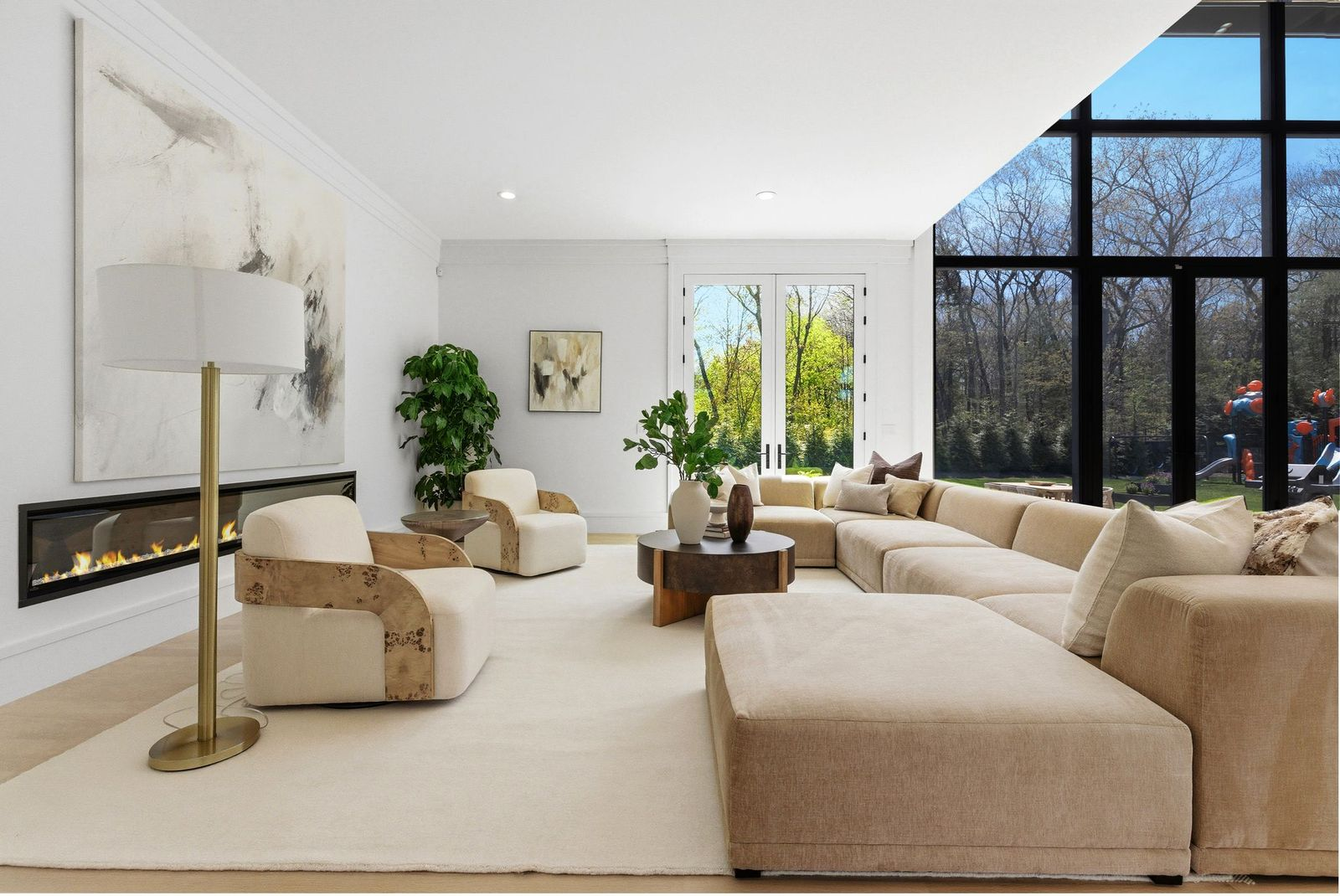 Floor-to-ceiling black-framed windows and glass doors along one side of the room bring in natural light and provide views of the backyard.