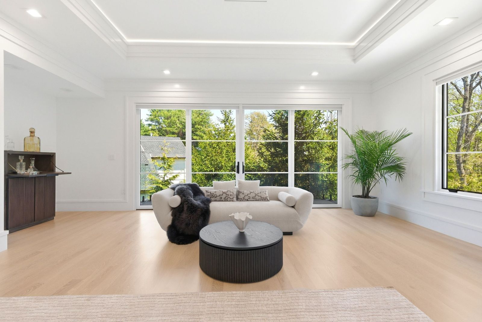 On the other side of the bed, floor-to-ceiling windows and oversized sliding glass doors sit behind another lounge centered around a plush sofa and round coffee table.