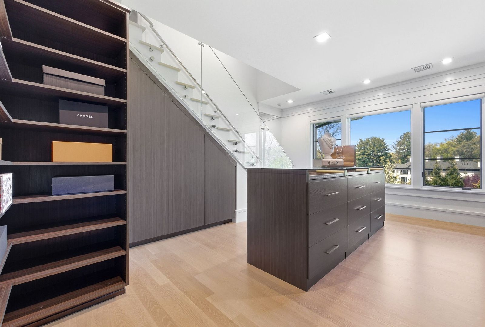 Connected to the bedroom is a two-story walk-in closet designed with dark wood cabinetry that lines the walls and a large storage island.