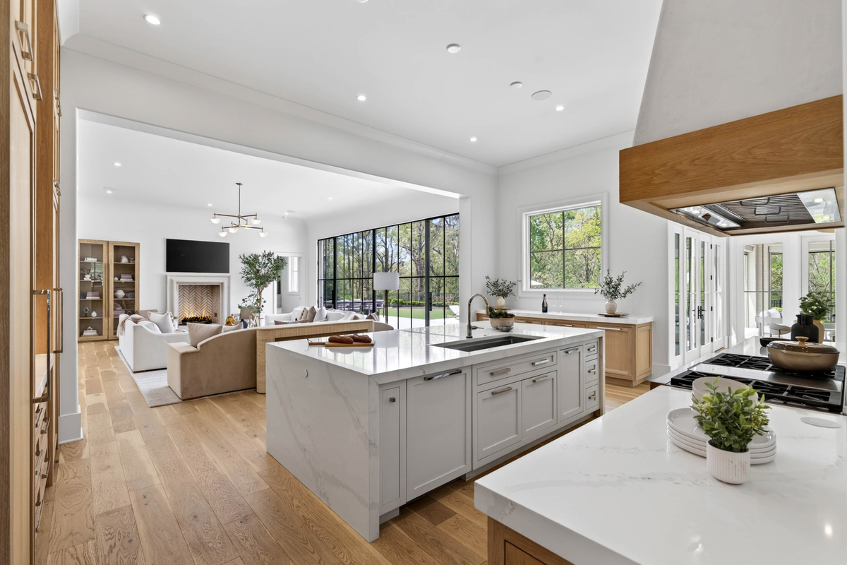 Behind the great room, the home transitions into a chef's kitchen centered around a waterfall-edge quartz island with an integrated sink and seating.