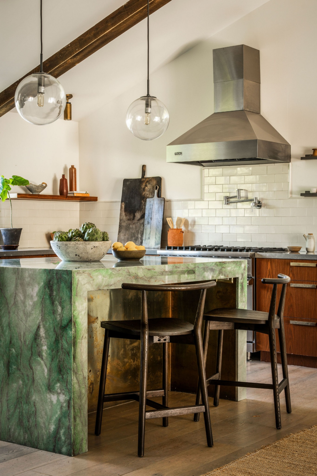 At the center is a large green quartzite island that doubles as both a prep station and casual gathering spot, complete with seating tucked beneath one side. 