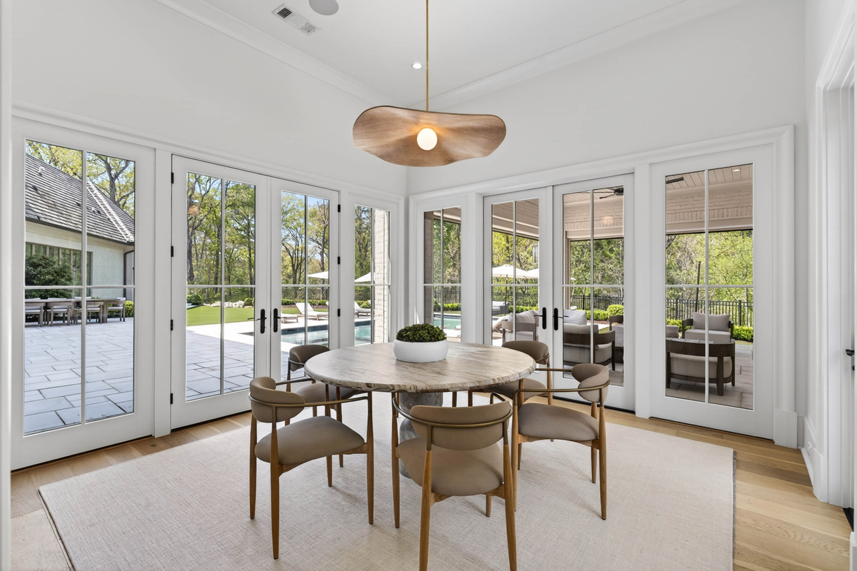 Within the space, a round dining table sits beneath a sculptural pendant light, creating an intimate space for casual meals.