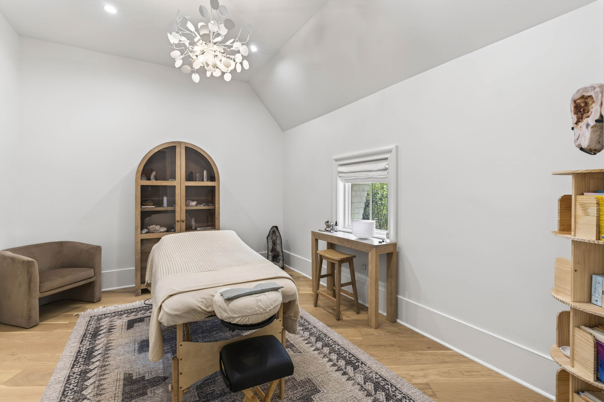 Vaulted ceilings create a sense of openness, while soft lighting, wood accents, and a dedicated treatment table give the room the atmosphere of a private spa.