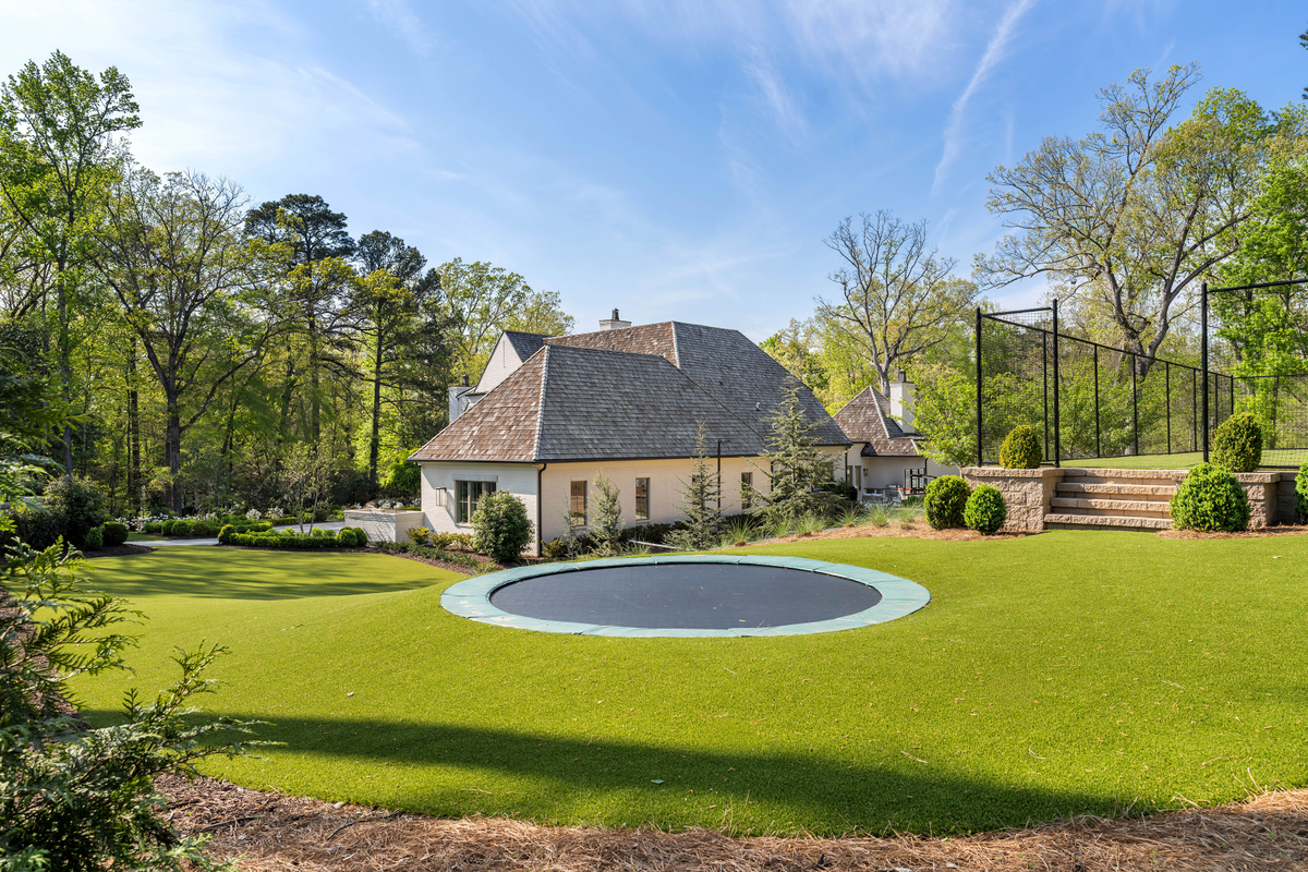 Lastly, at the edge of the property is an in-ground trampoline surrounded by turf and mature landscaping.