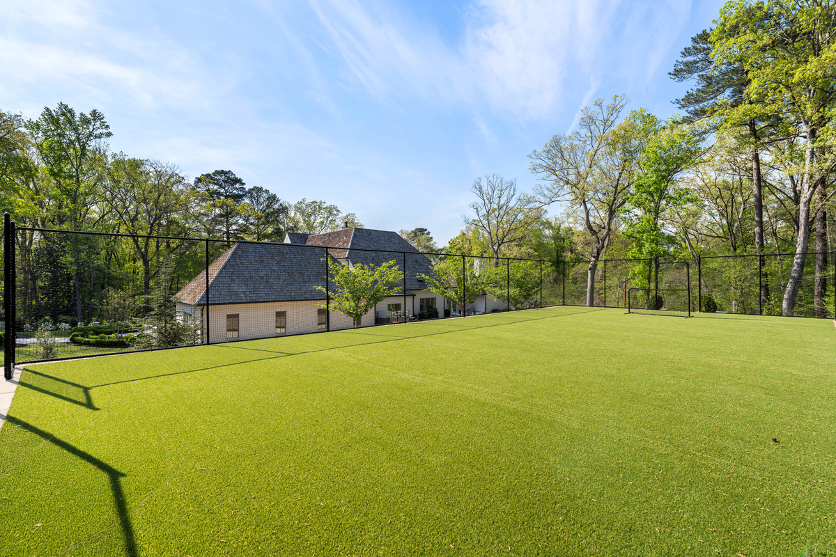 Up a few steps from the sports court and occupying one of the highest points of the property is a fully enclosed turf field surrounded by protective fencing.
