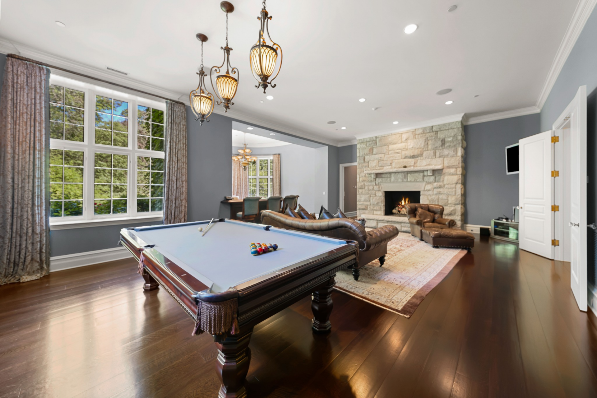 A dedicated game room centers around a full-size billiards table positioned beneath decorative pendant lighting. 