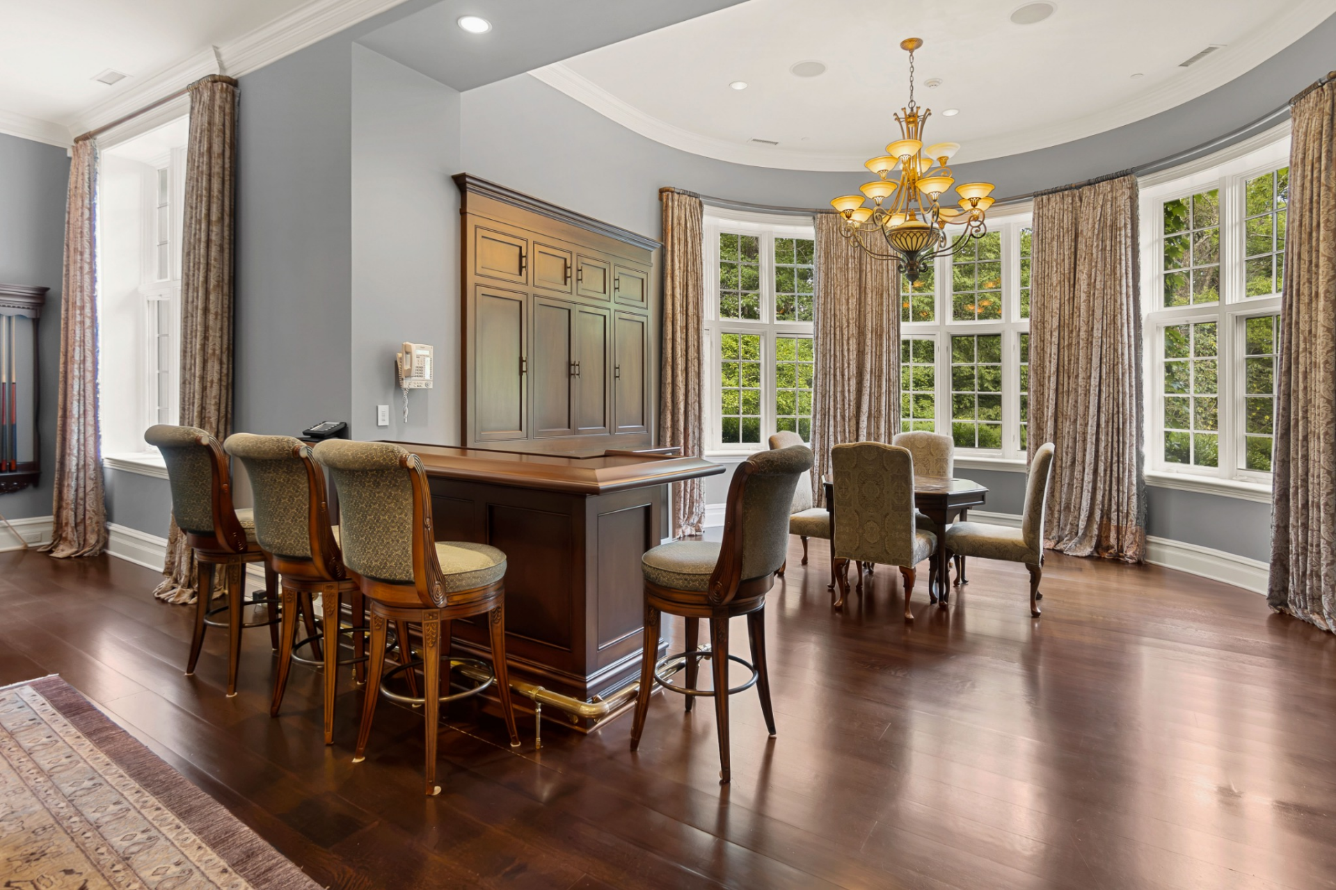A custom wet bar and card-playing nook occupy a curved bay of windows overlooking the grounds.