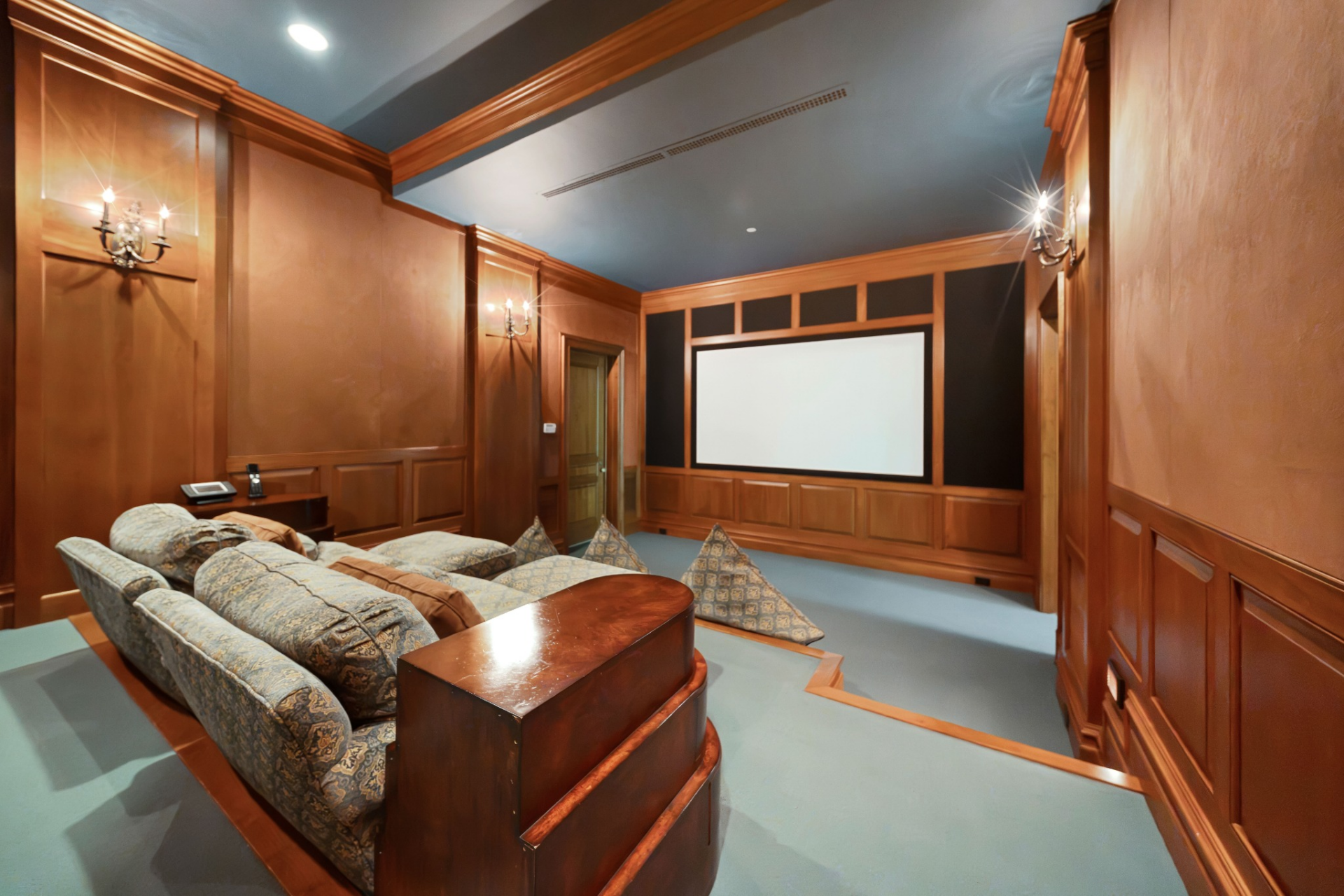 The theater is designed as a private screening room with tiered seating arranged toward a large projection screen.