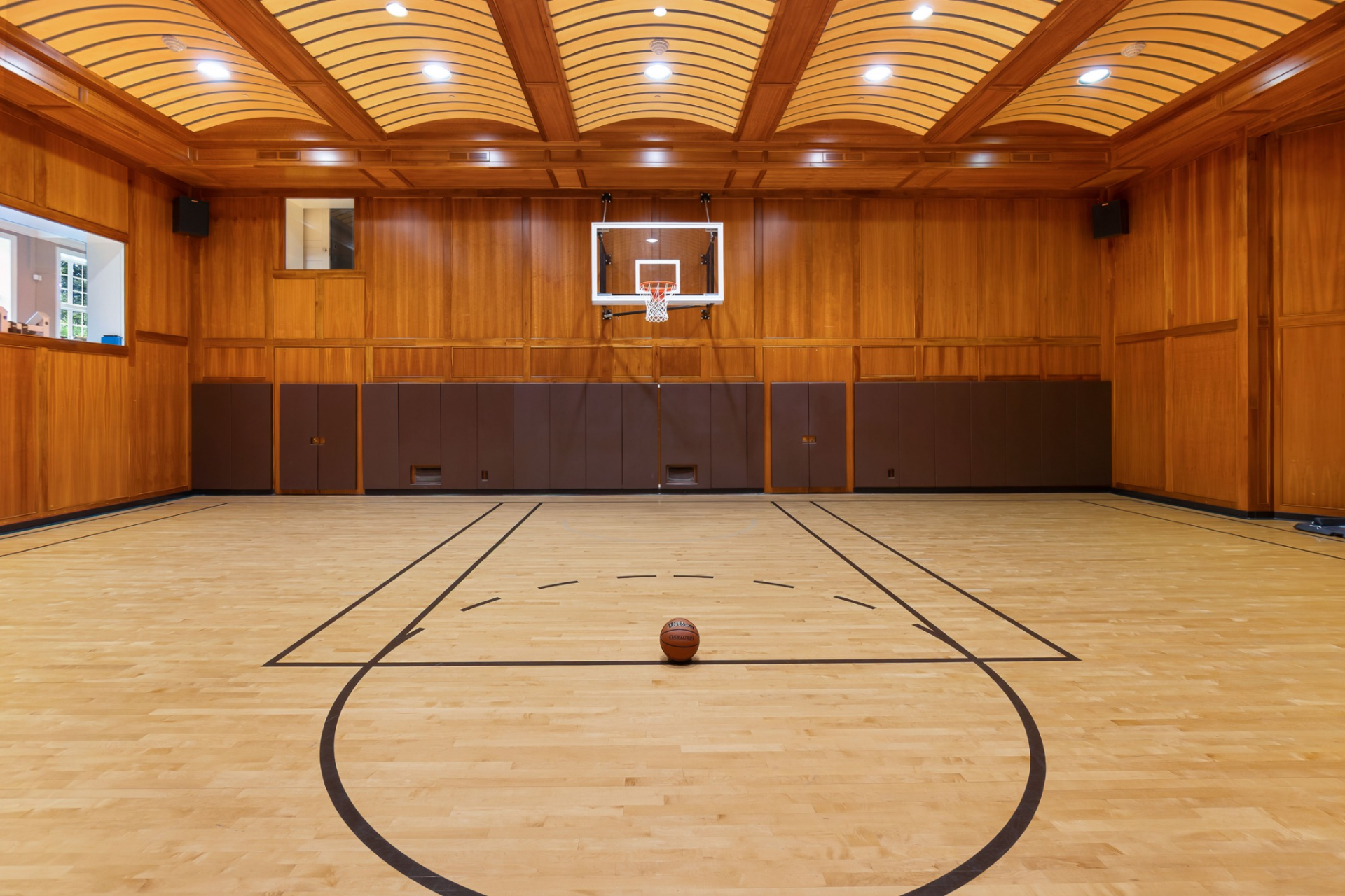 Finished with hardwood flooring and wood-paneled walls, the court includes a regulation-style hoop and an NBA three-point line.
