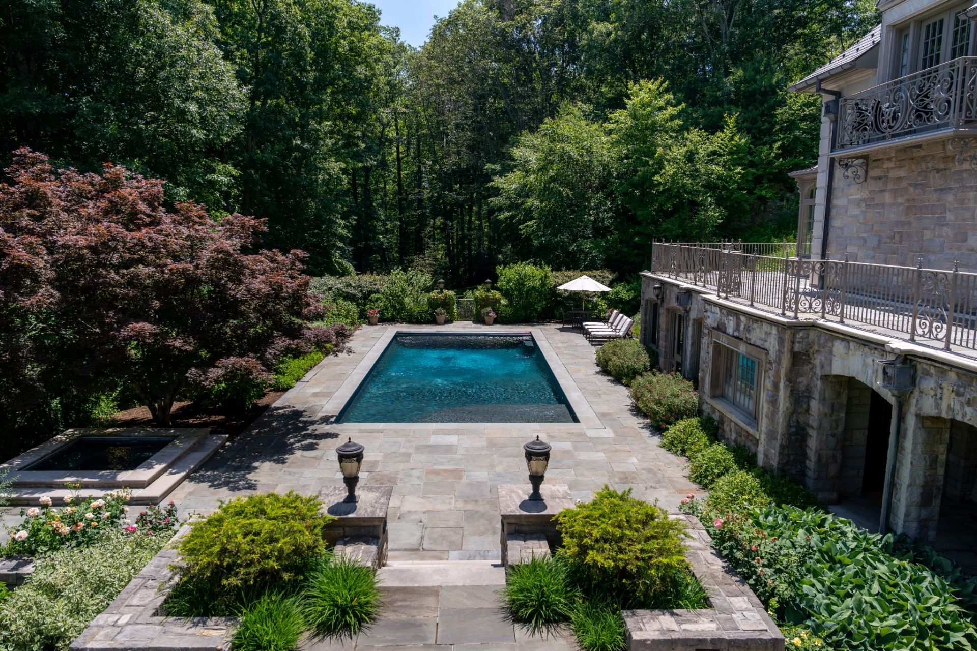 At the center of the backyard is a heated rectangular swimming pool accompanied by a separate spa. 