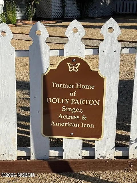A plaque along the white picket fence acknowledges this is the former home of Dolly Parton.